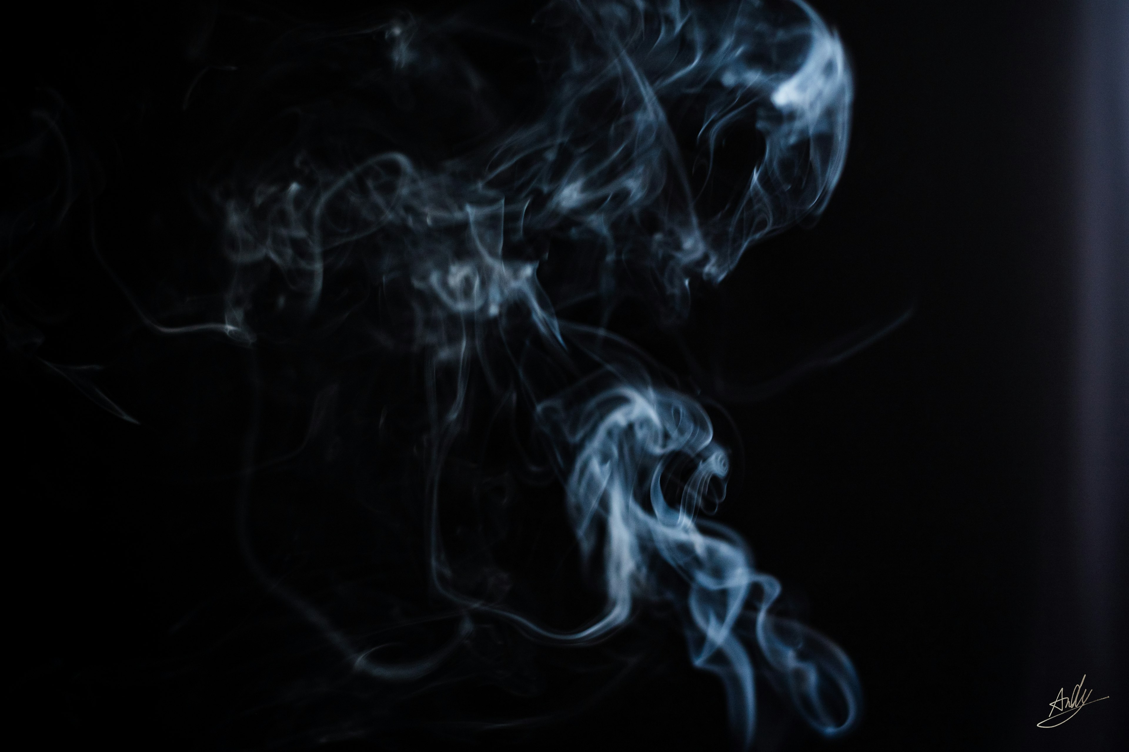 Artistic shapes of blue smoke against a black background