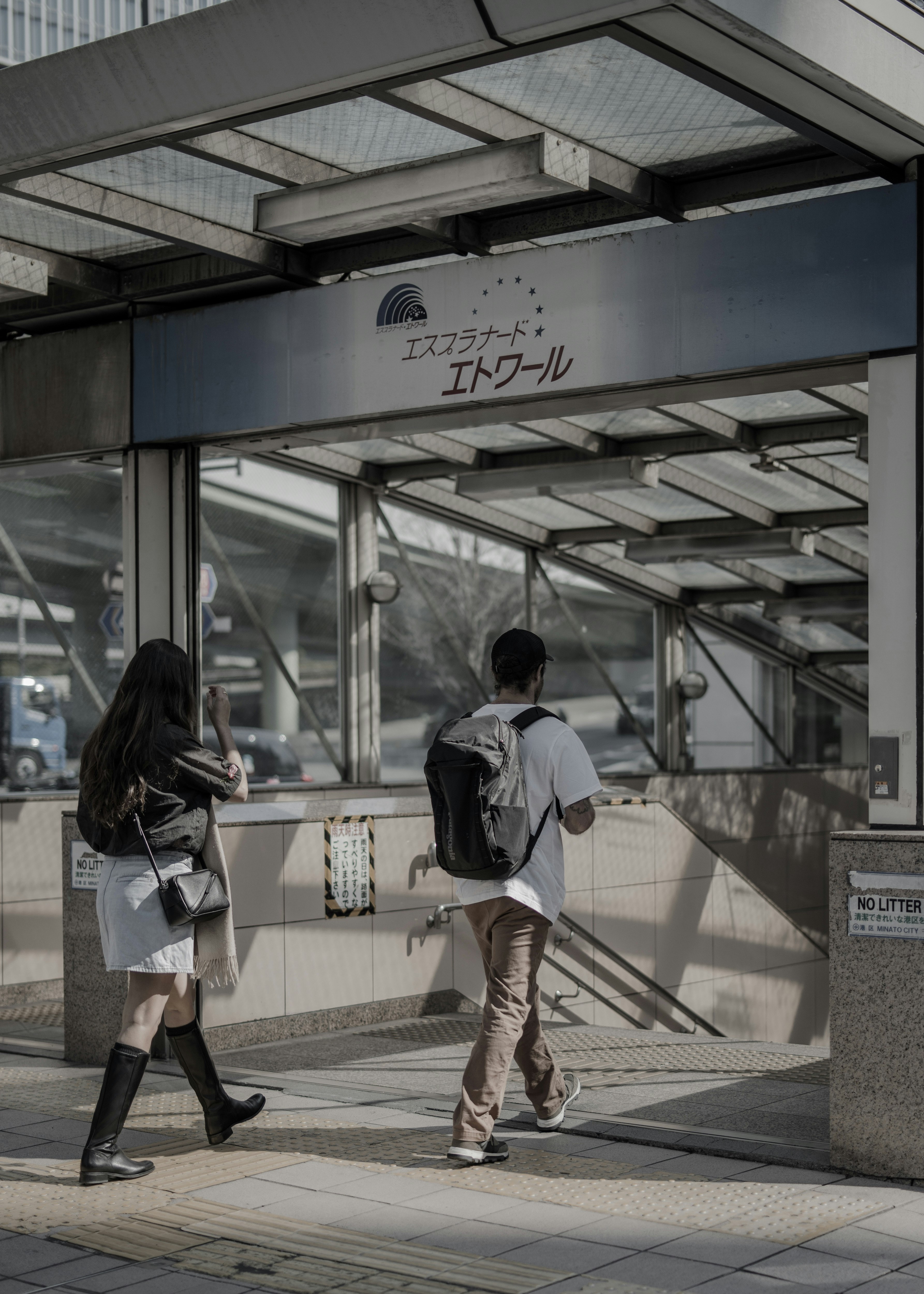 Two young individuals walking towards a train station entrance