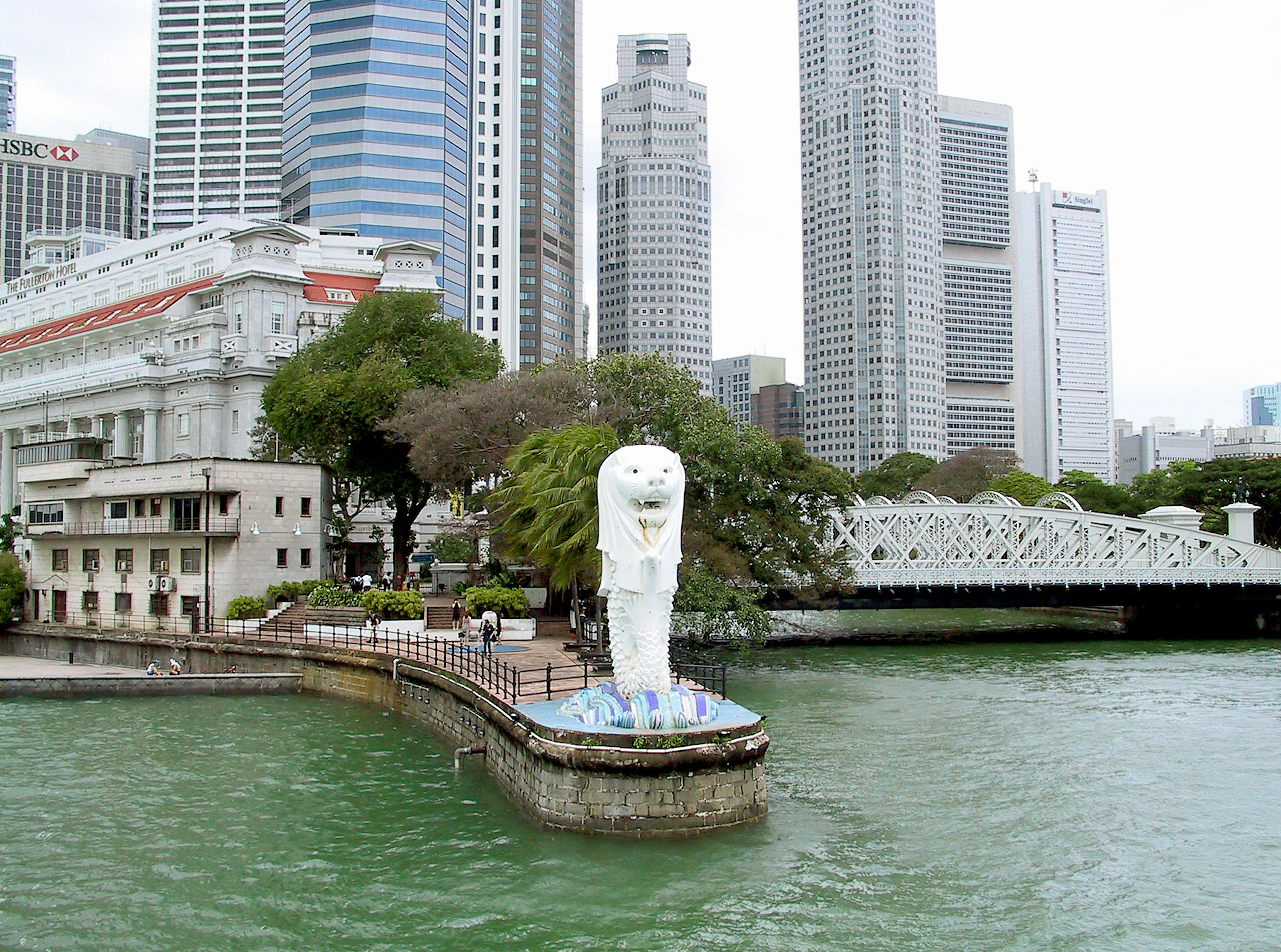 Patung Merlion di Singapura dekat tepi laut dengan gedung pencakar langit di latar belakang