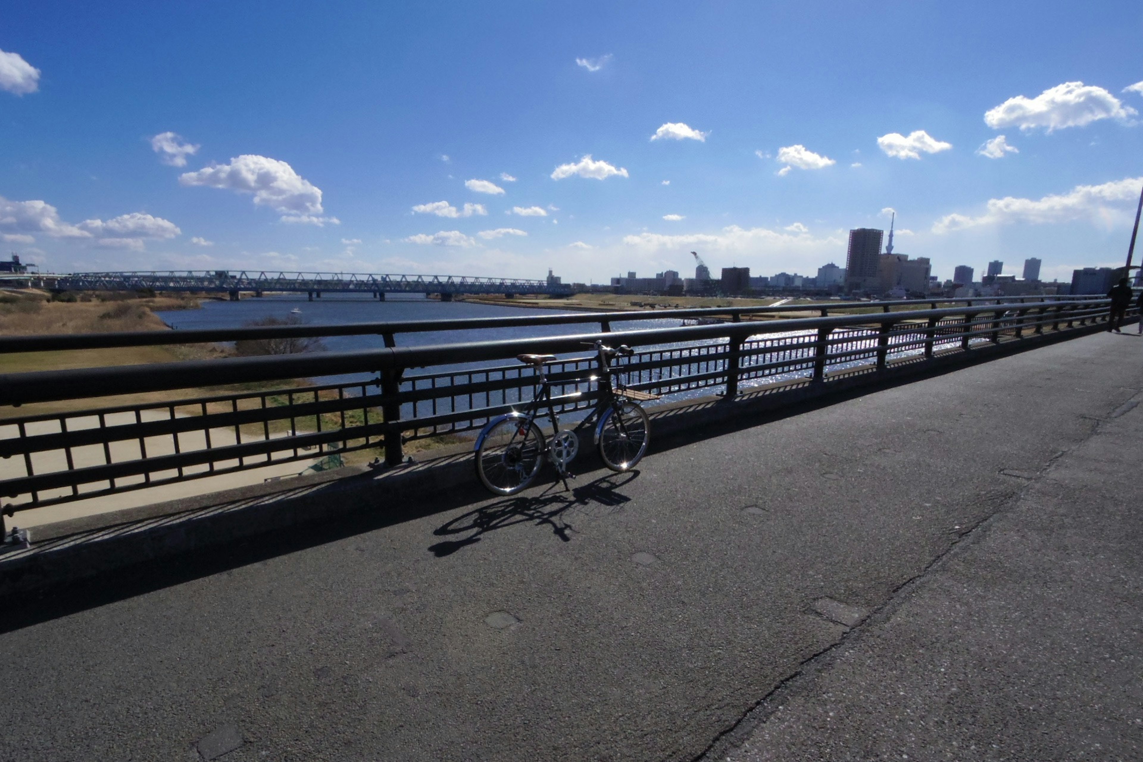 Bicycle parked by the river under a blue sky