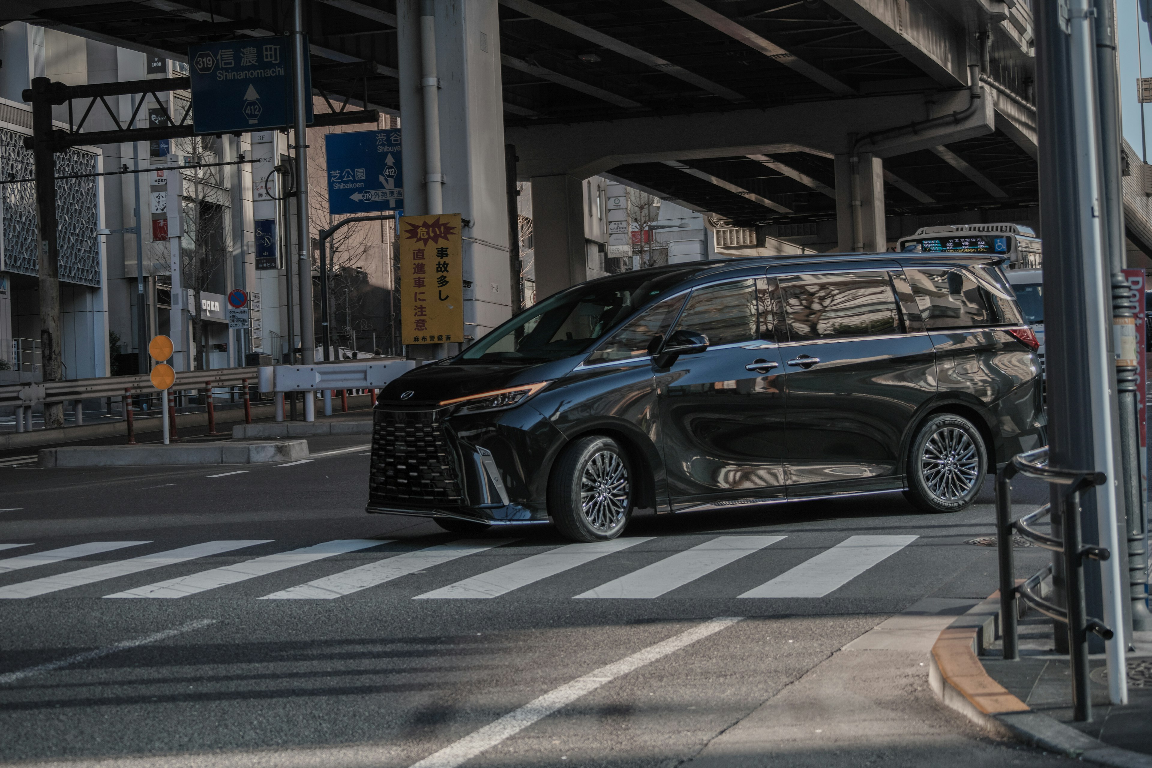 Minivan nero che attraversa un attraversamento pedonale in un contesto urbano