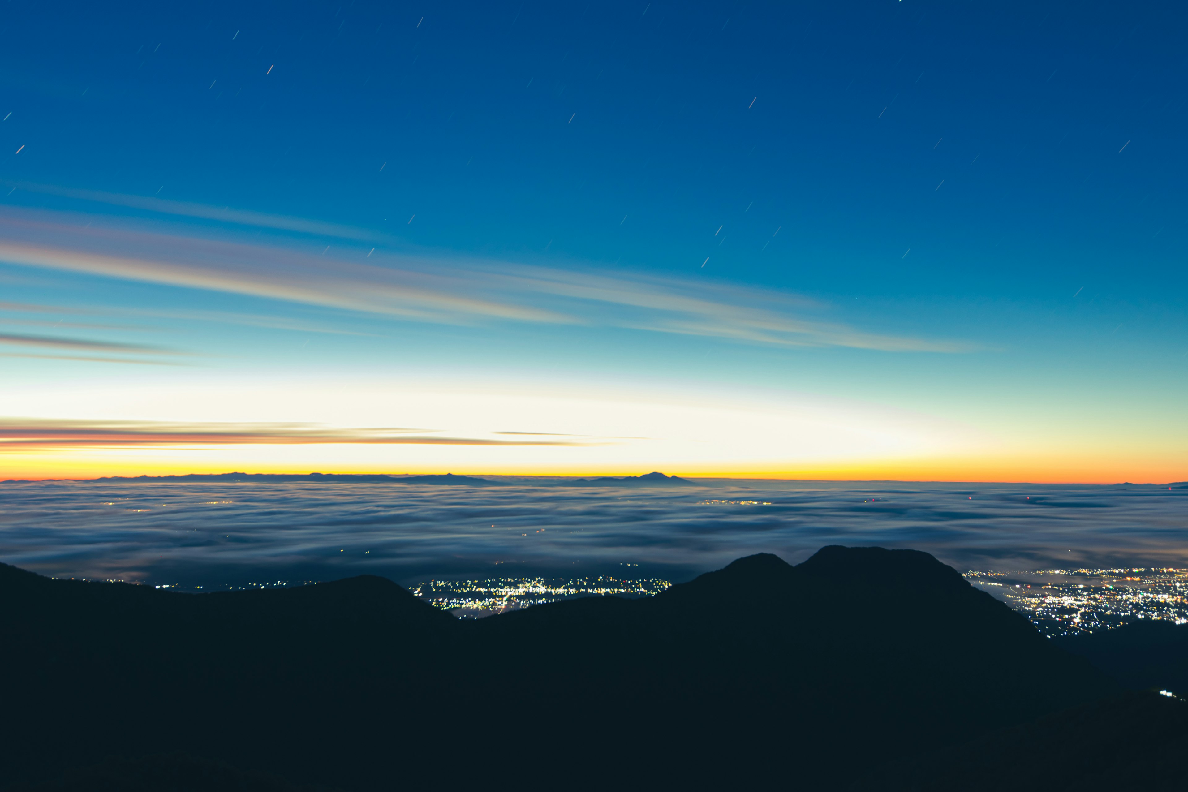 Stunning sunrise view with silhouettes of mountains and sea of clouds