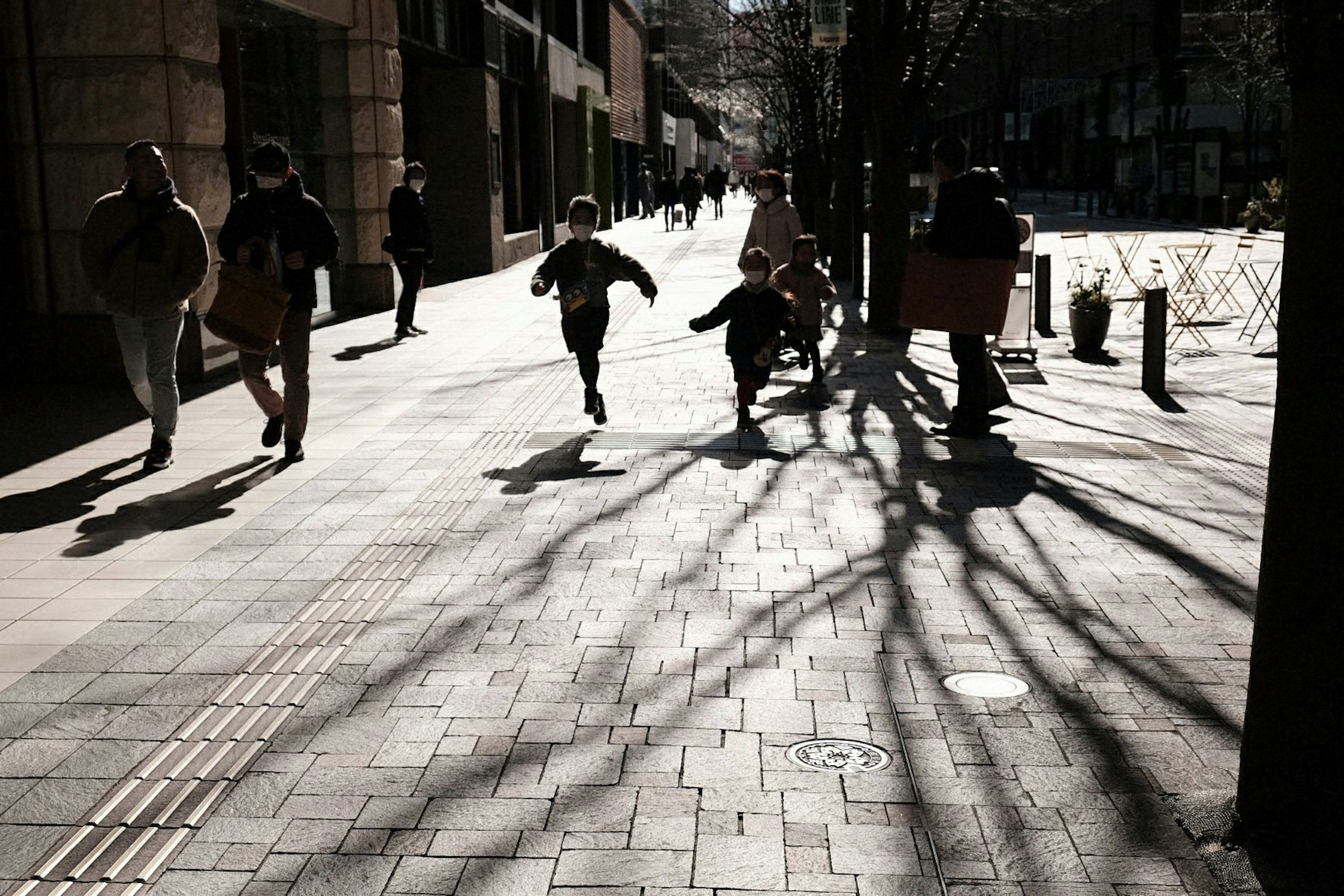 子供たちが走っている街の風景 日差しの影が地面に映る