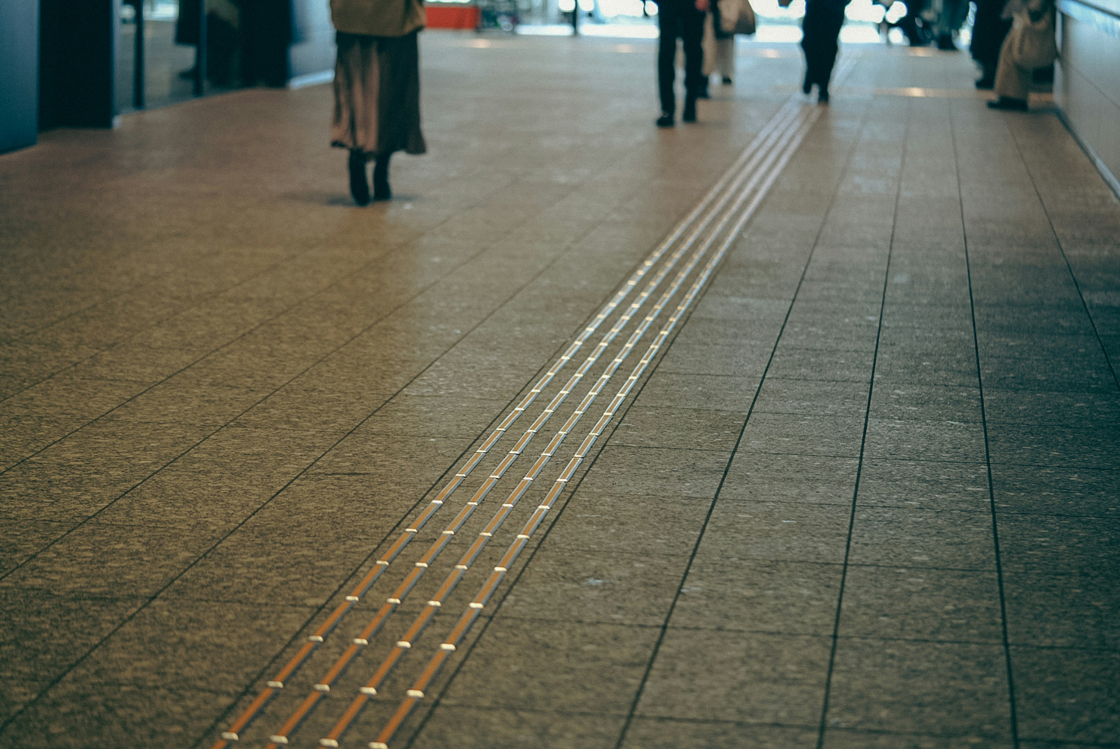 Un pasillo con líneas metálicas y personas caminando