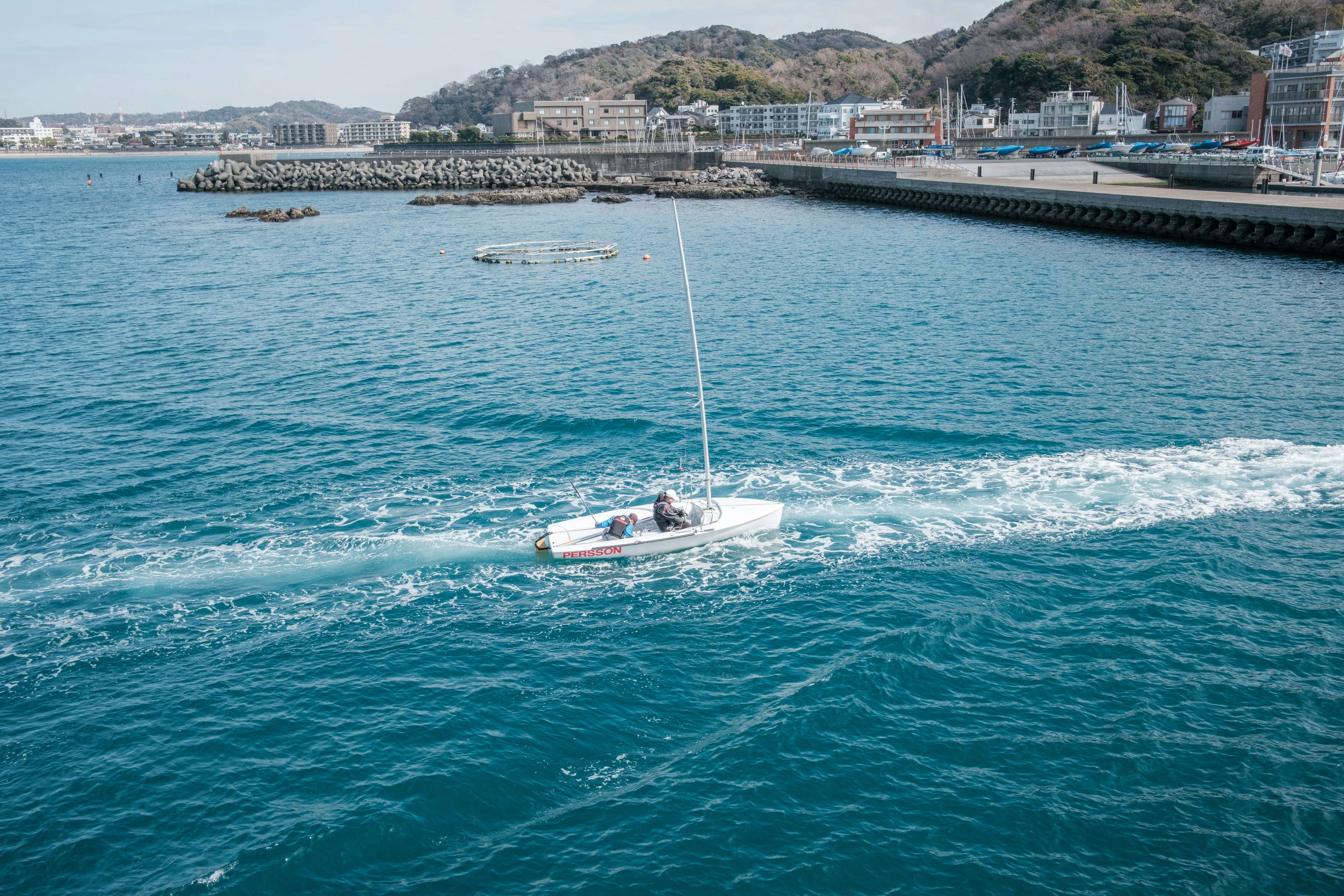 Pequeño barco navegando por aguas azules con vista costera