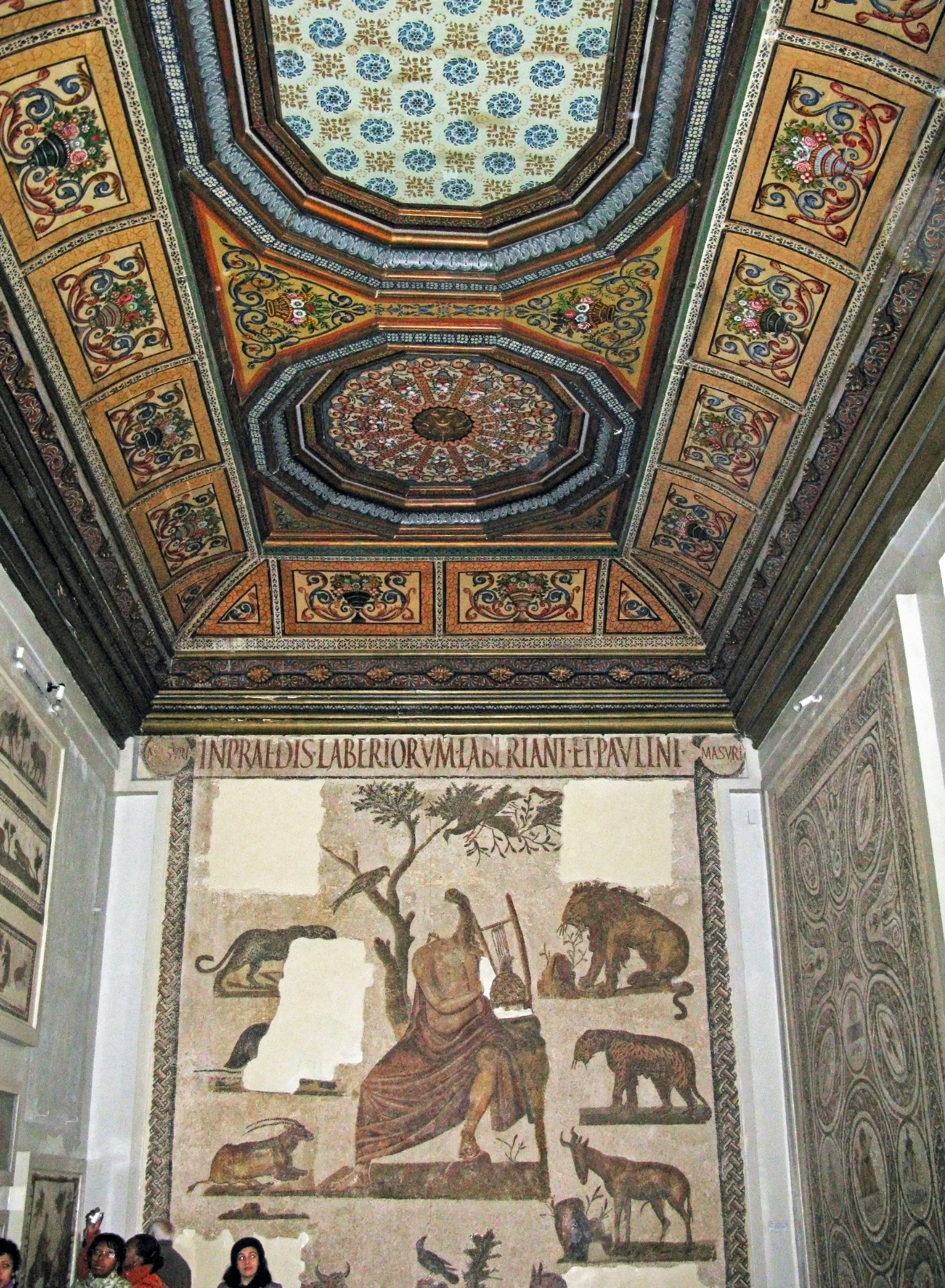 Room featuring an intricately decorated ceiling and a mosaic wall depicting various animals