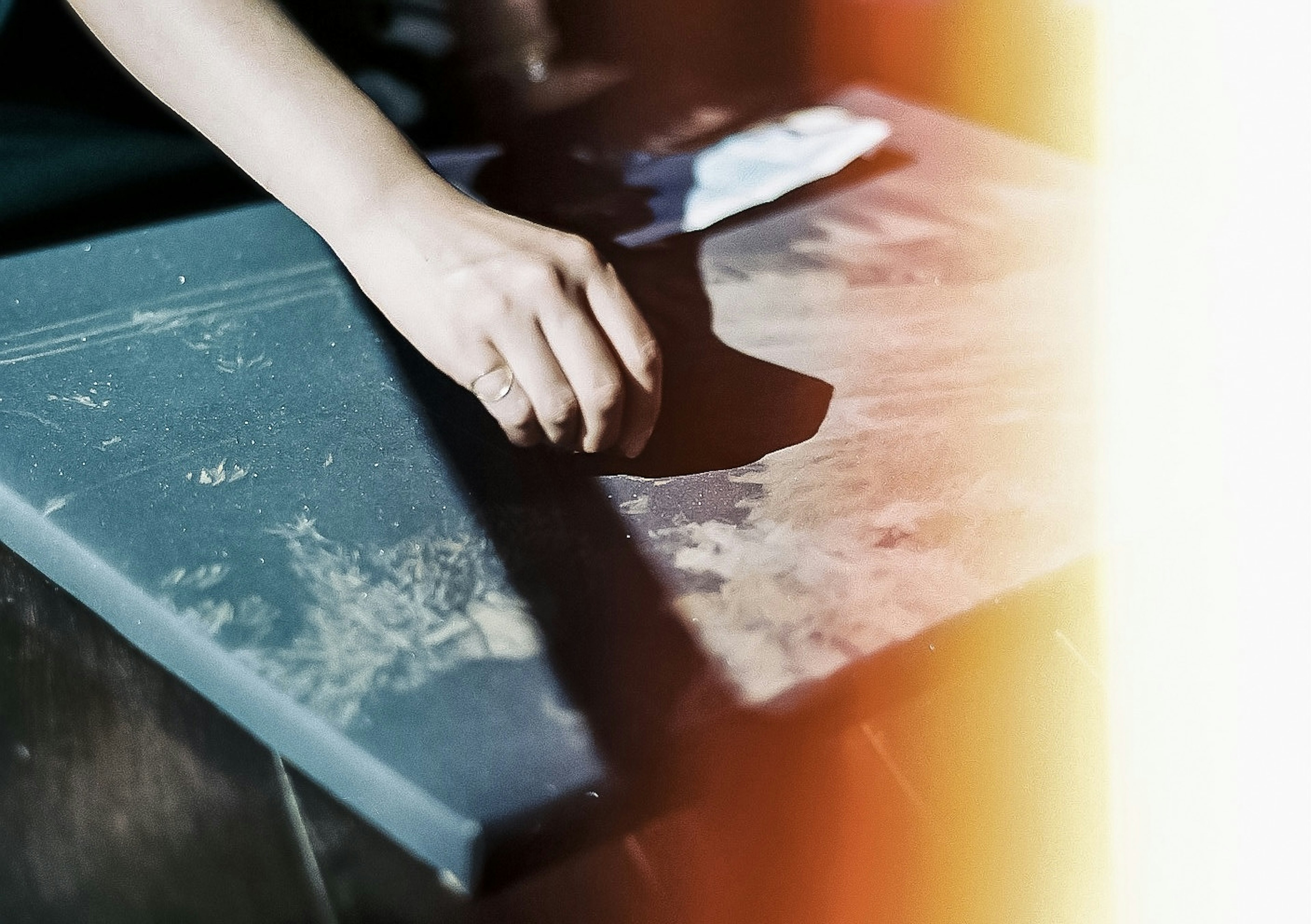 A hand resting on a dusty black board