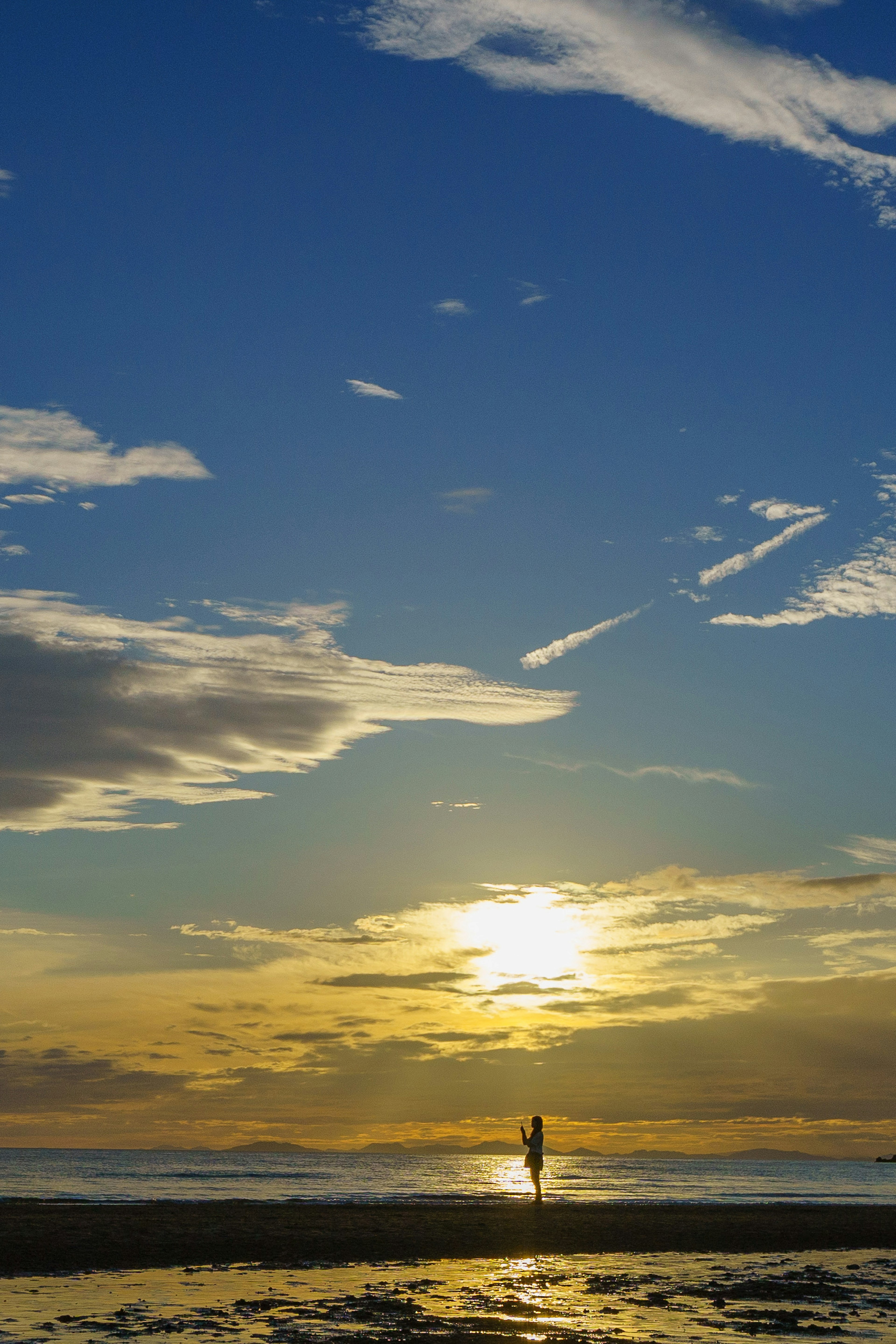 Silhouette of a person at the beach against a sunset and beautiful sky