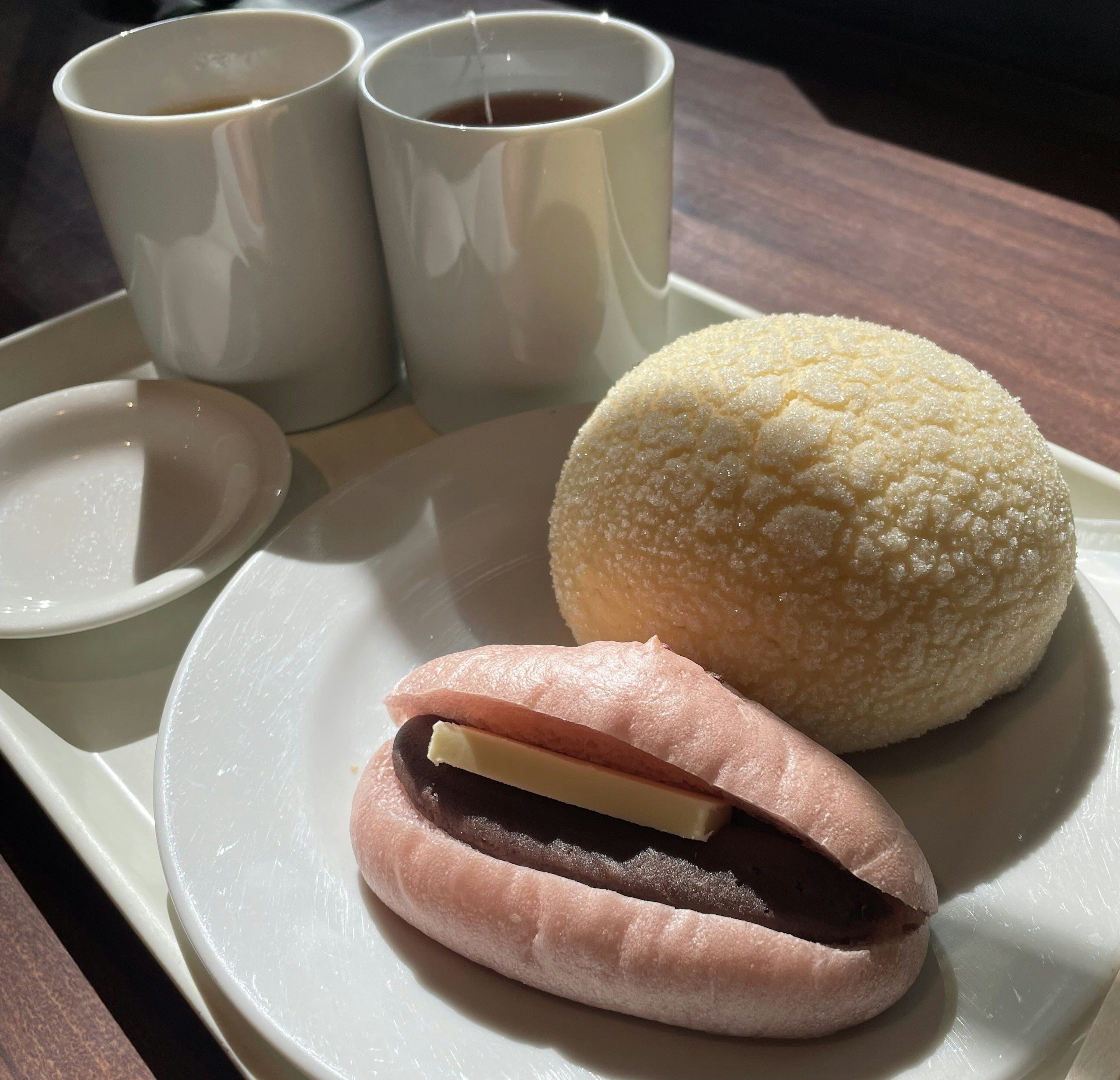 Dos tazas de té con dos dulces japoneses en un plato