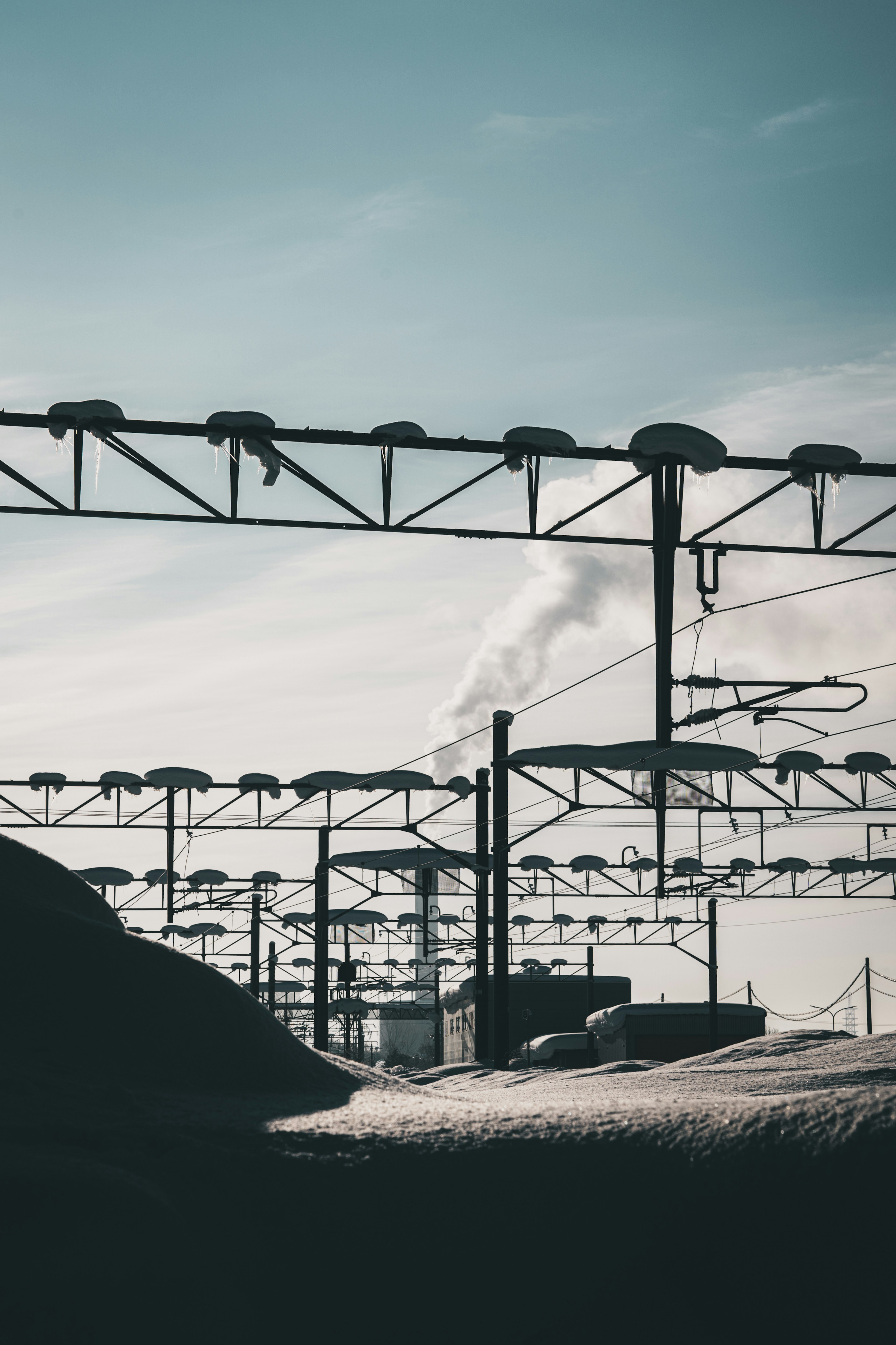 Industrial landscape featuring smoke from a chimney and overhead train lines