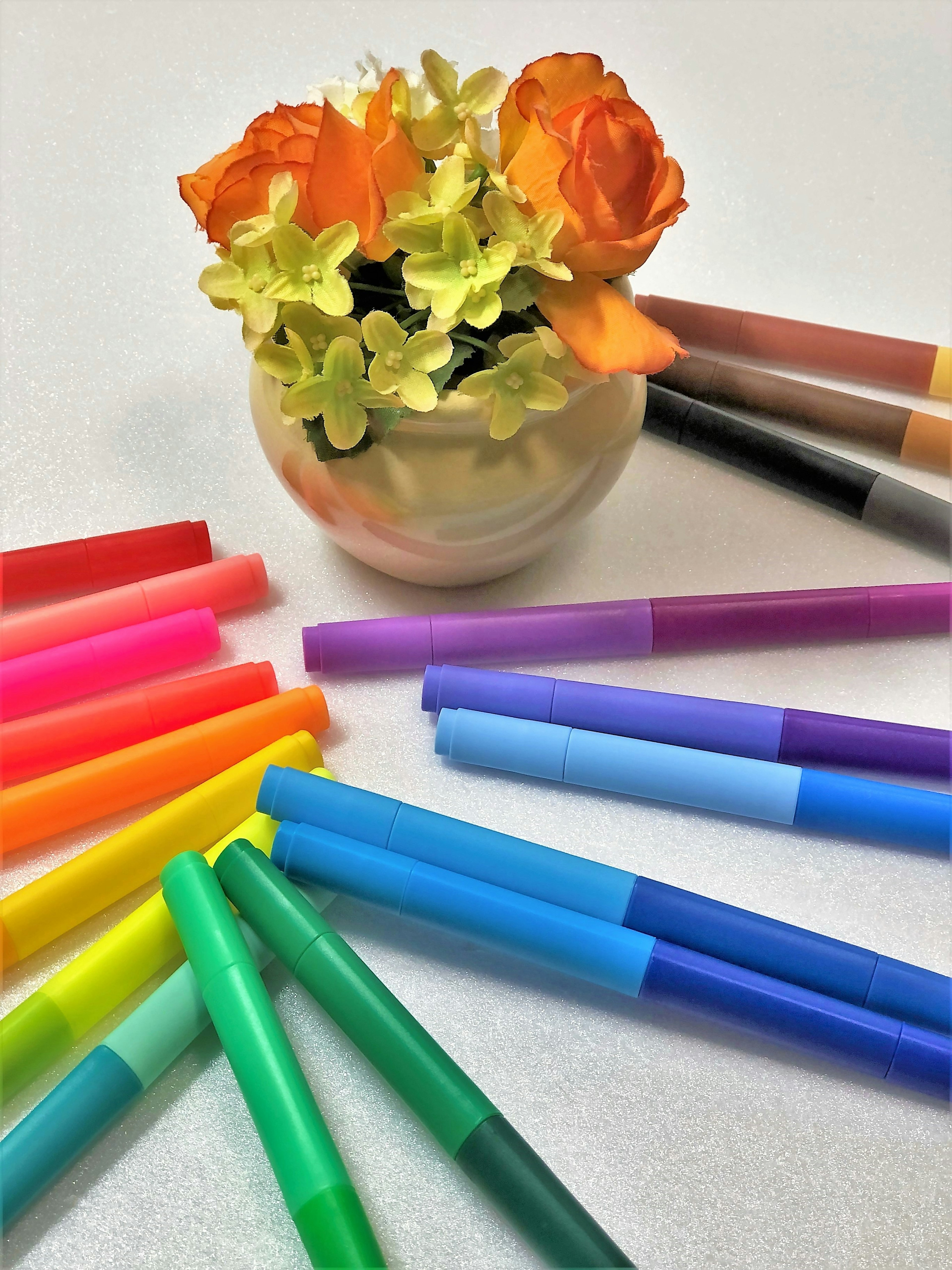 Bunte Marker um ein Blumenarrangement angeordnet