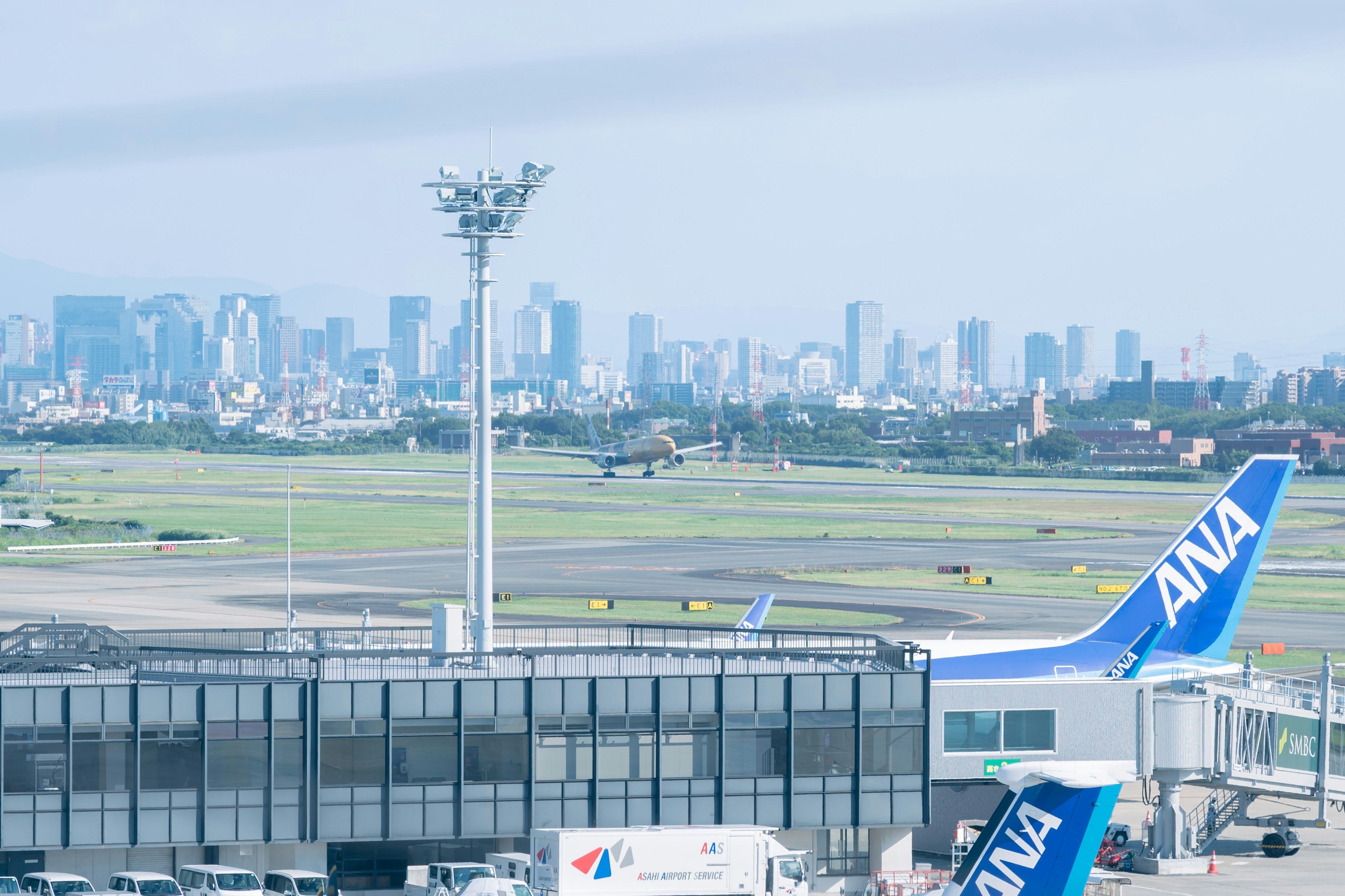 Pemandangan pesawat ANA di bandara Tokyo dengan latar belakang cakrawala kota