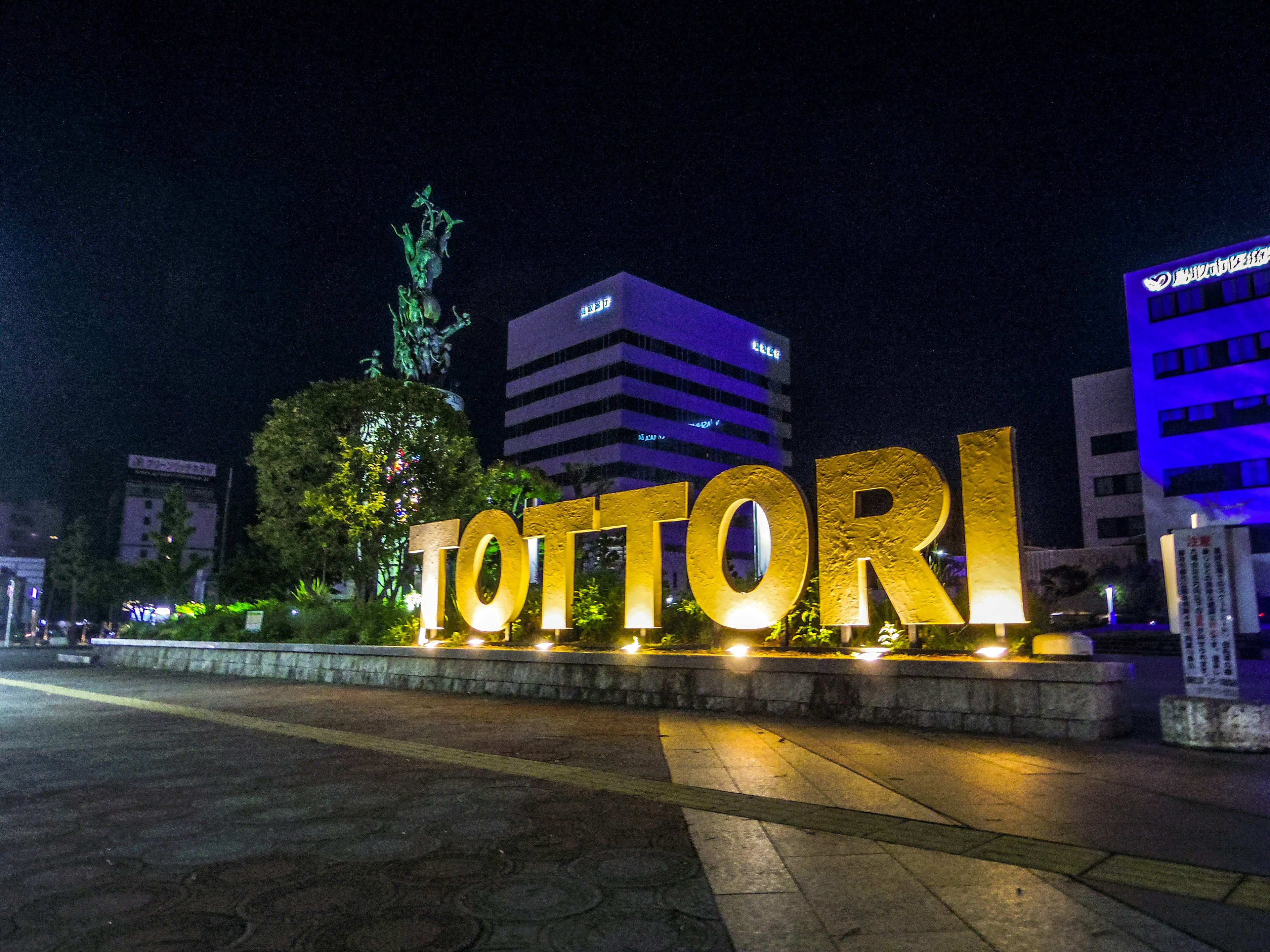 Illuminated Tottori sign at night with surrounding buildings