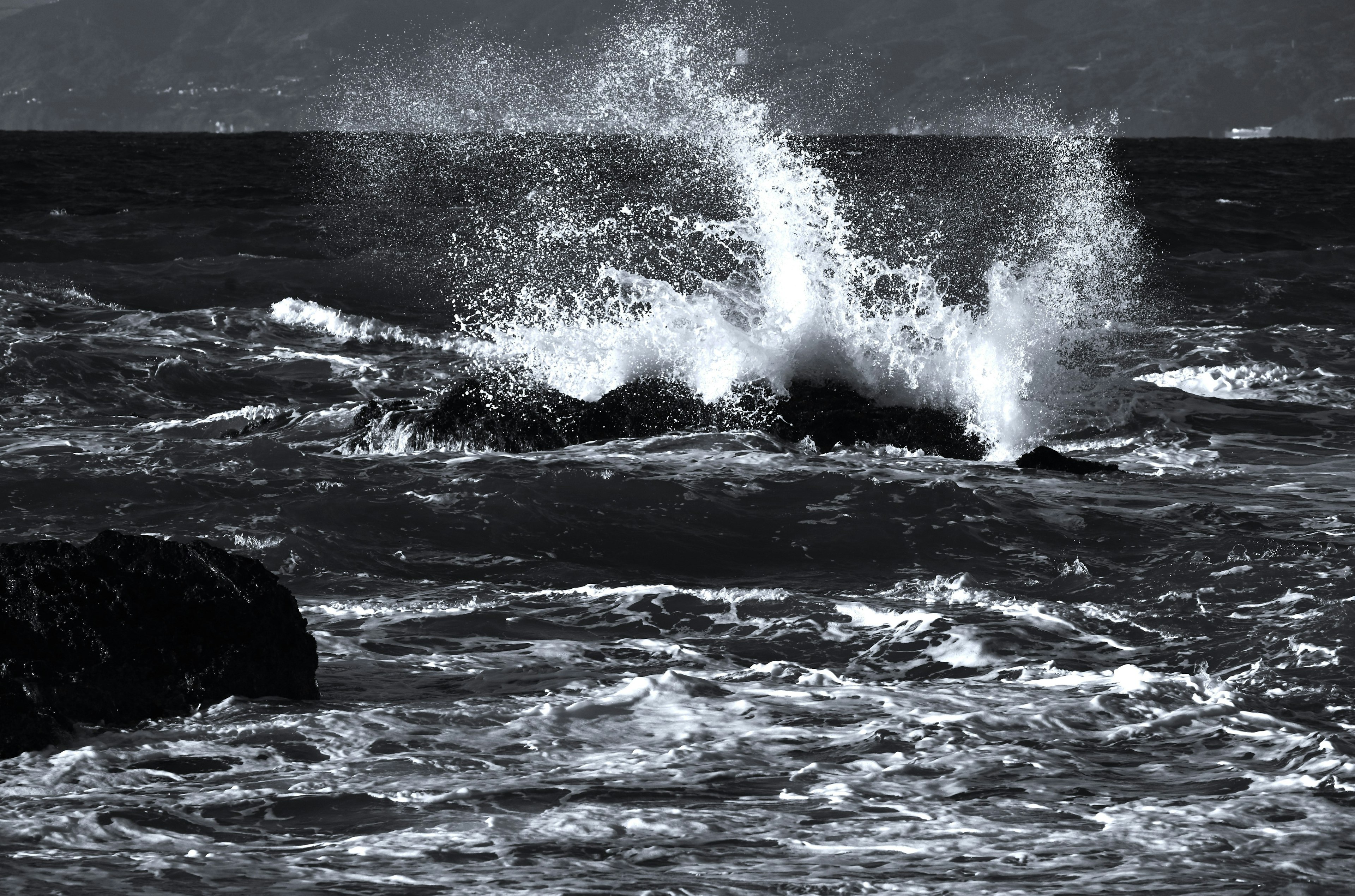 Black and white ocean waves crashing against rocks