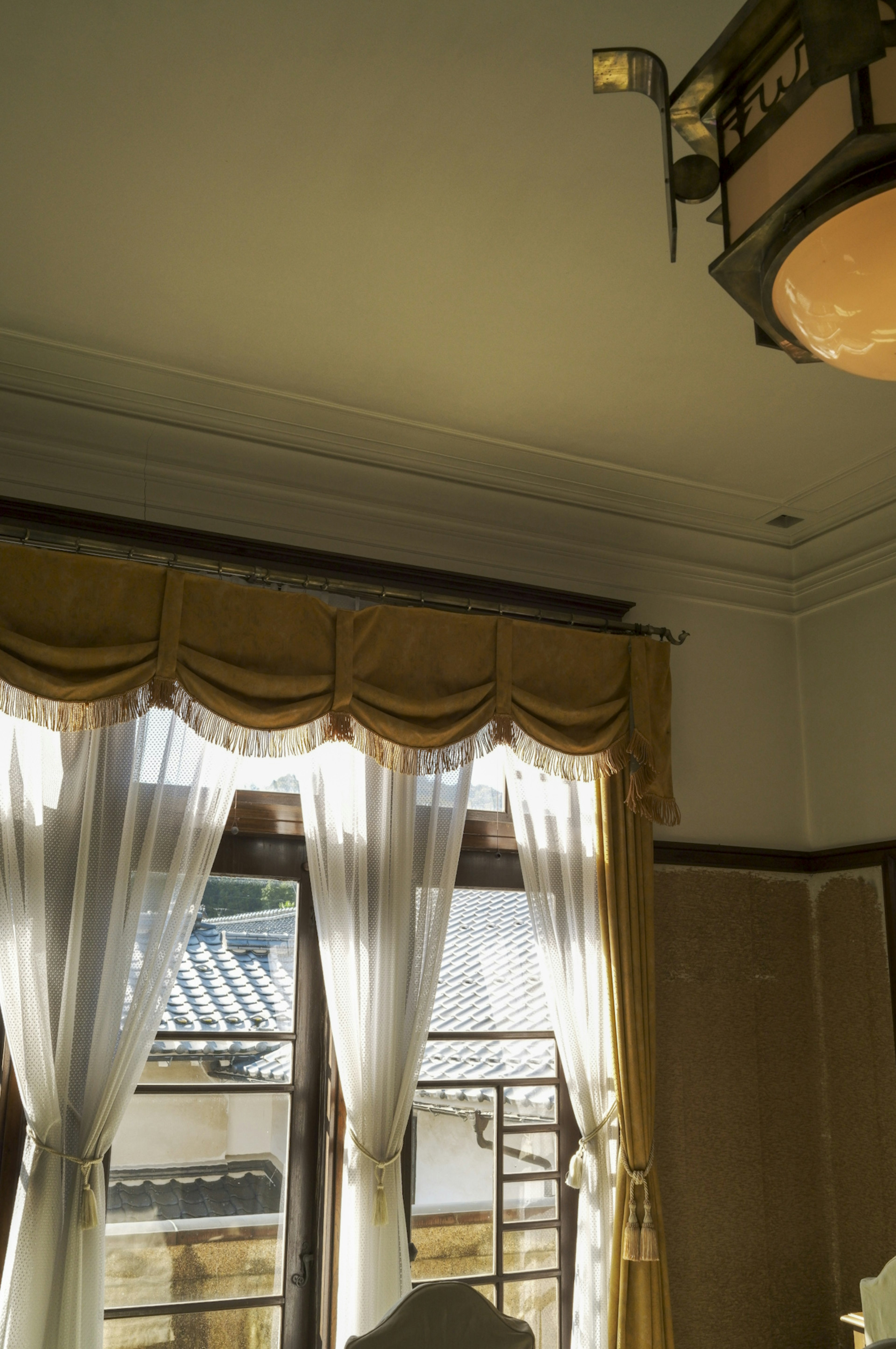 Corner of a room with bright curtains and a chandelier