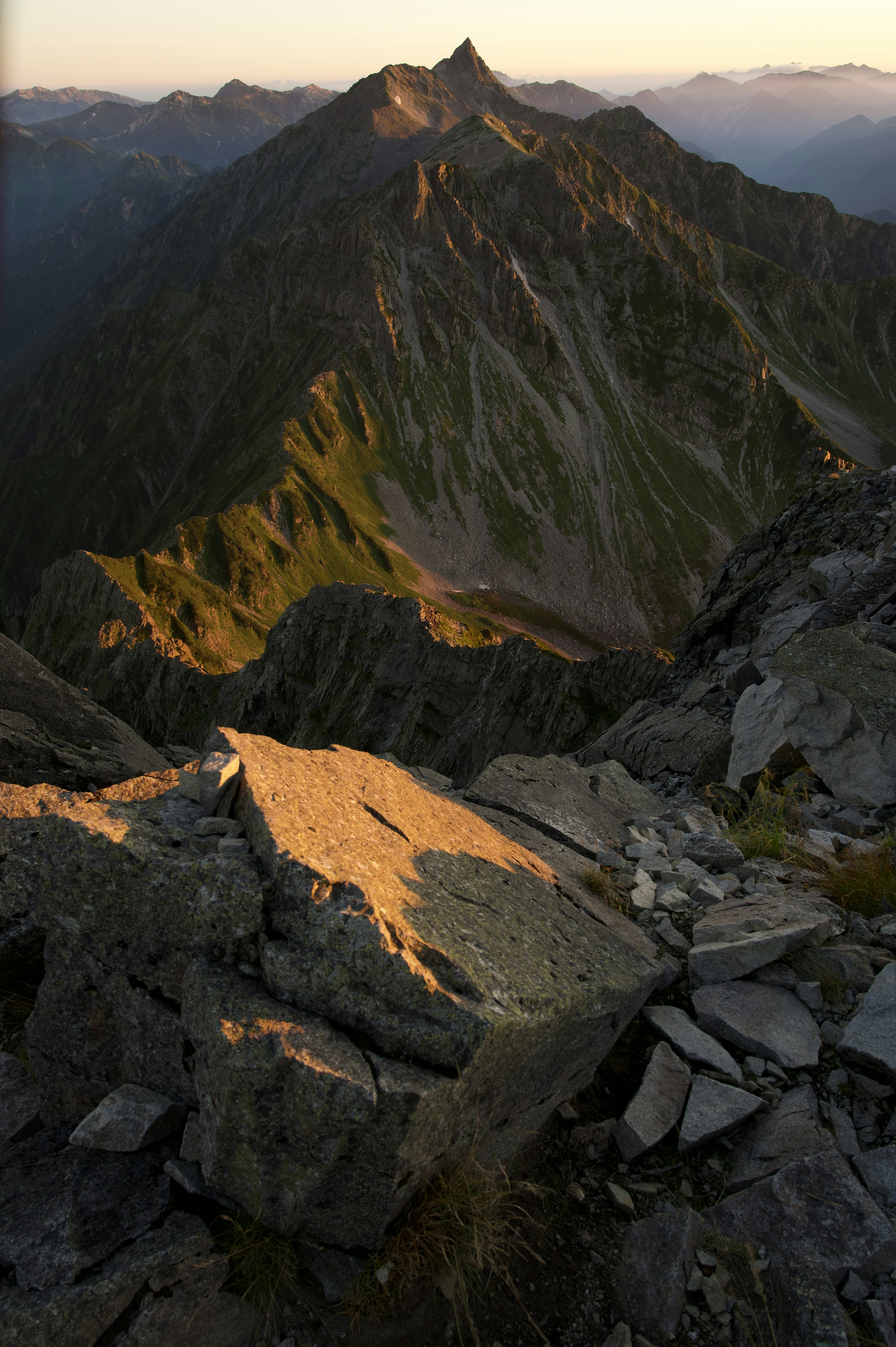 Mountain landscape with sunlight on rocks and steep slopes at sunset