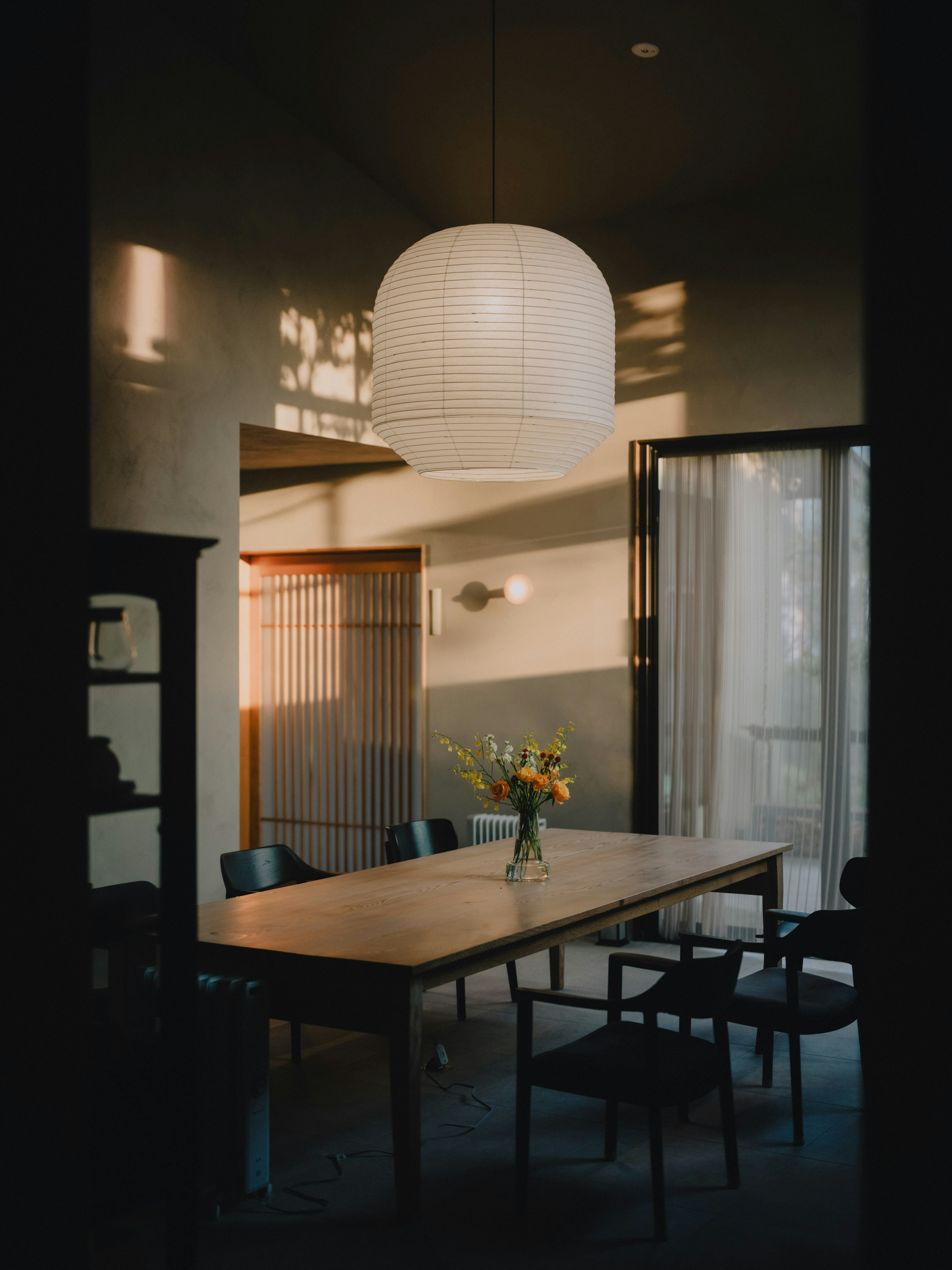 Un interior de comedor moderno y simple con iluminación brillante y una mesa de madera con un jarrón de flores