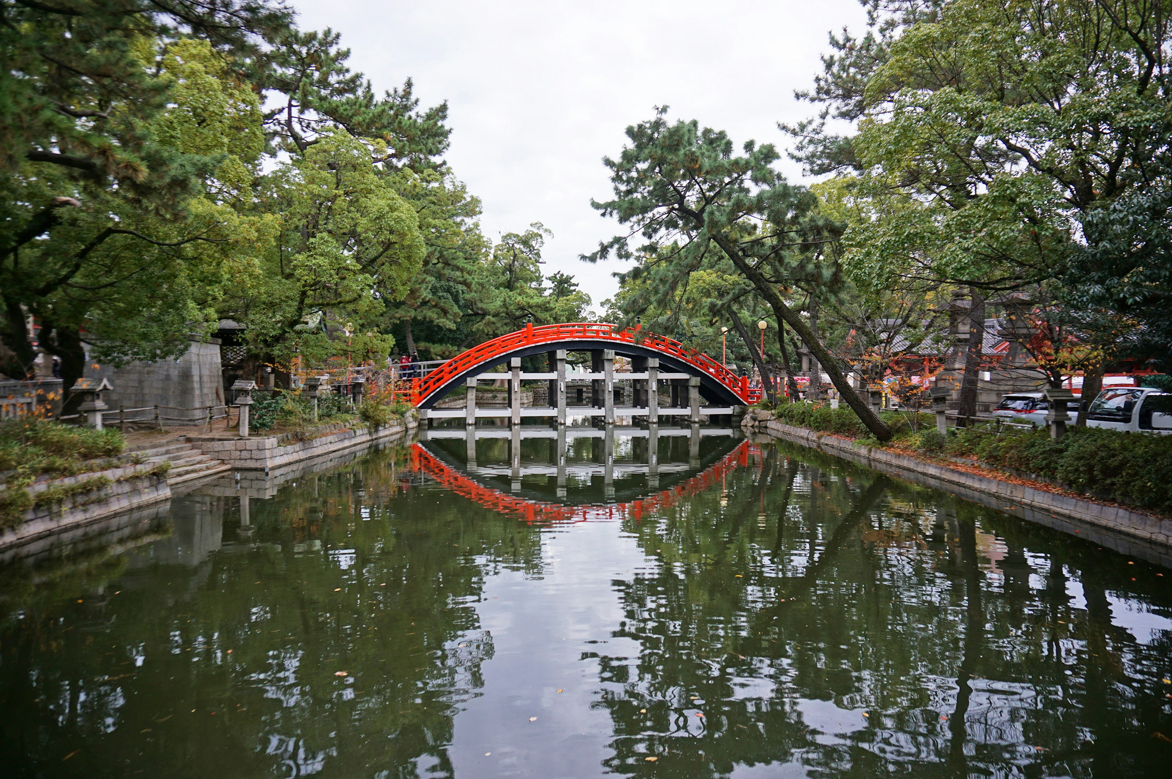 A serene pond with a red bridge reflecting on the water