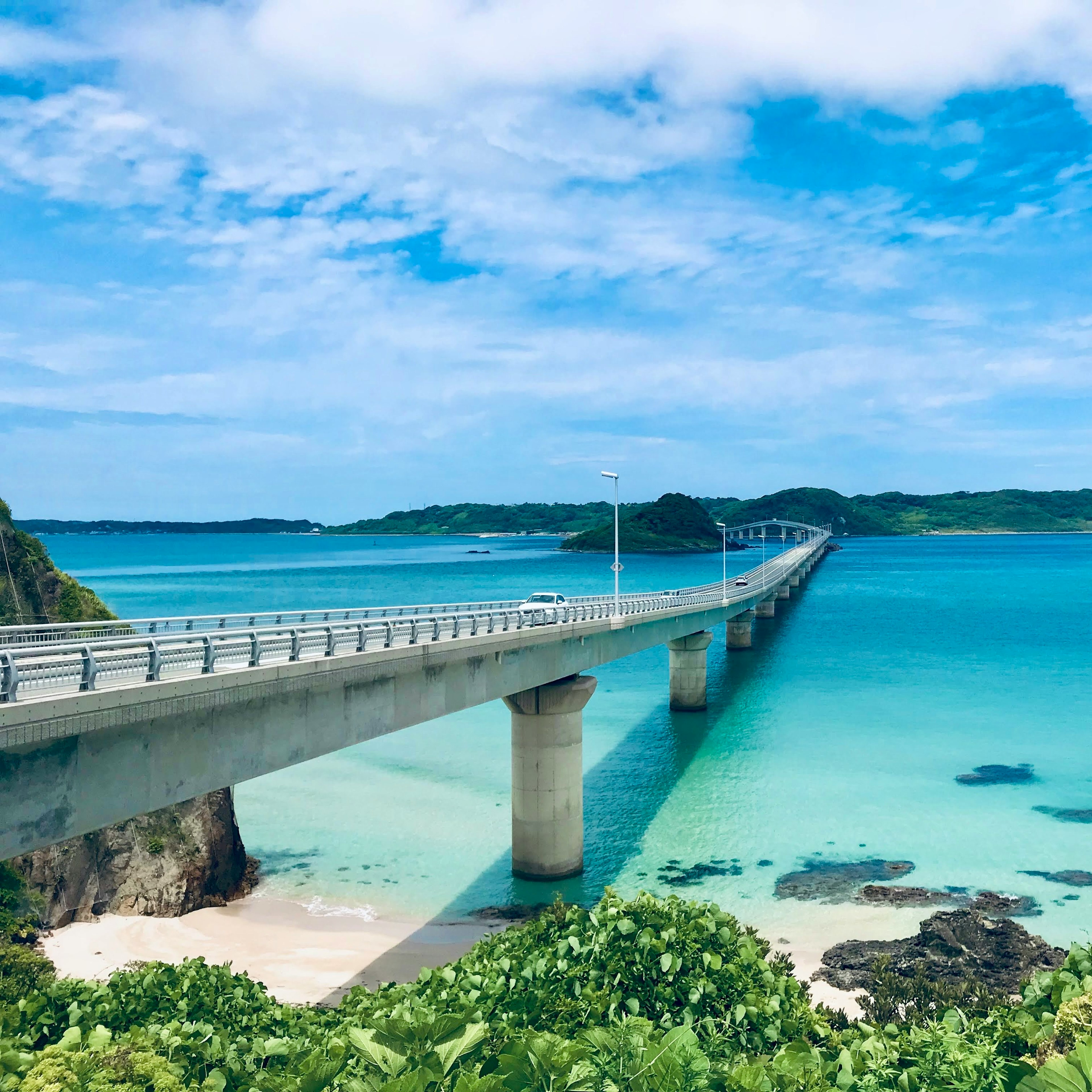 Pemandangan jembatan yang indah di atas air turquoise dengan vegetasi subur