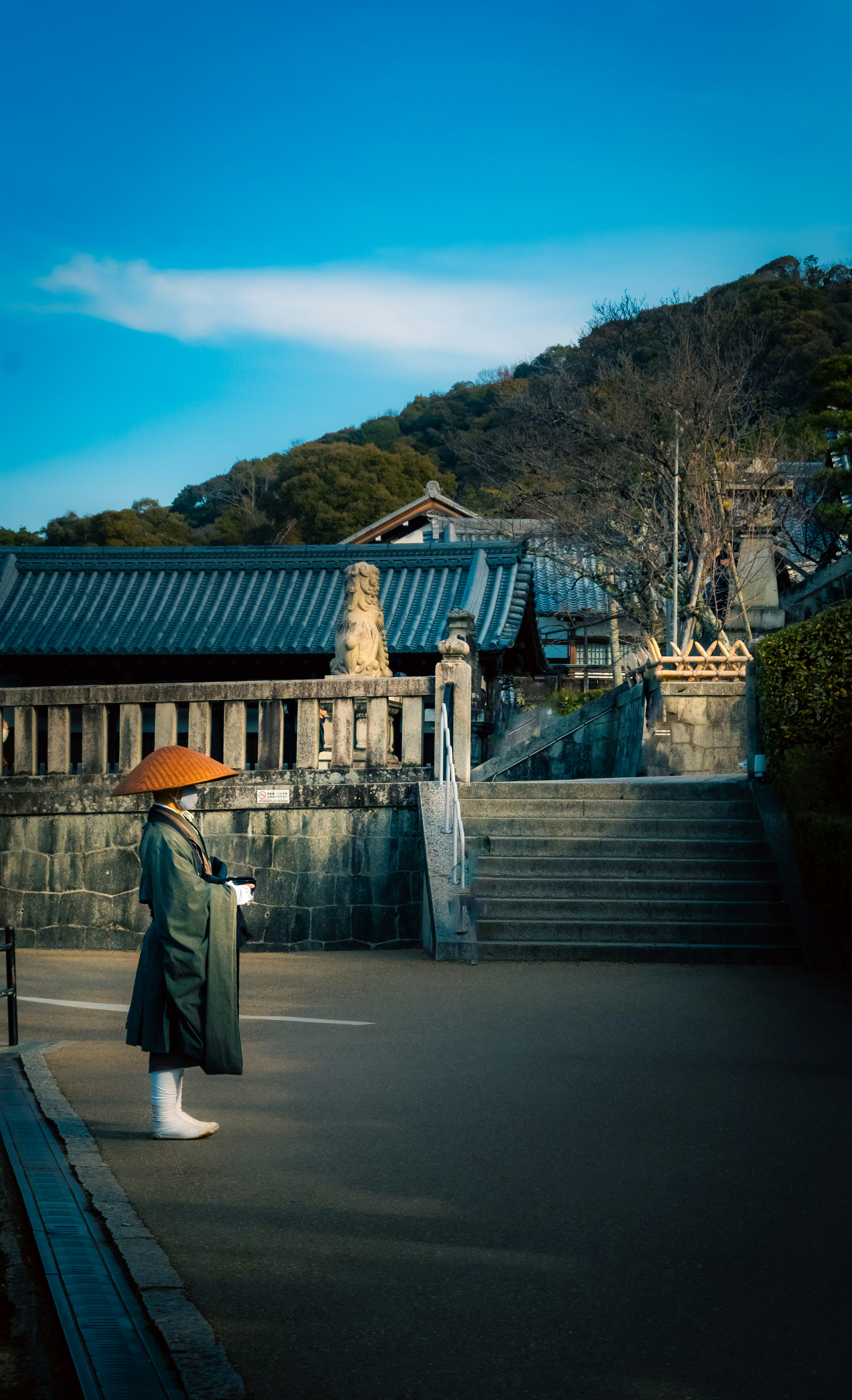 青空の下に立つ伝統的な衣装を着た人物と寺院の風景