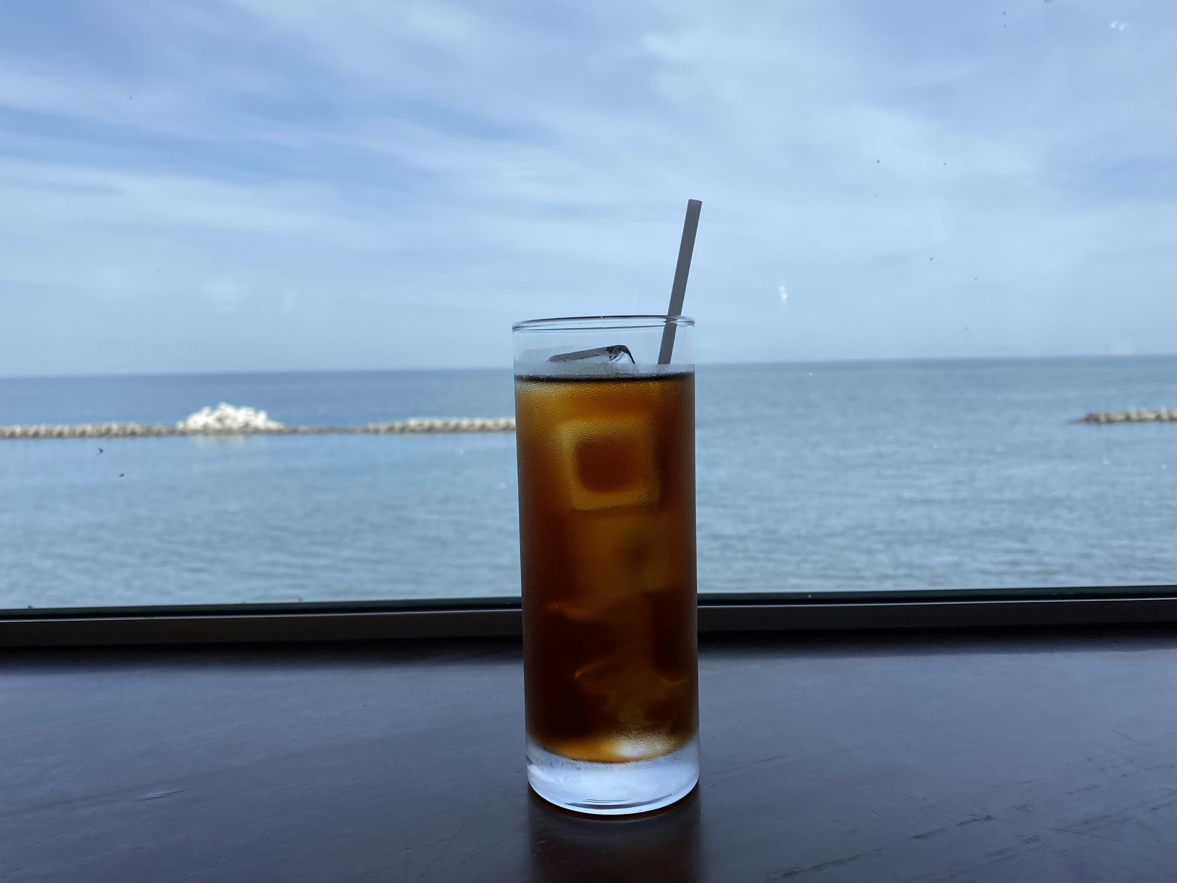 海を背景にしたアイスティーのグラス