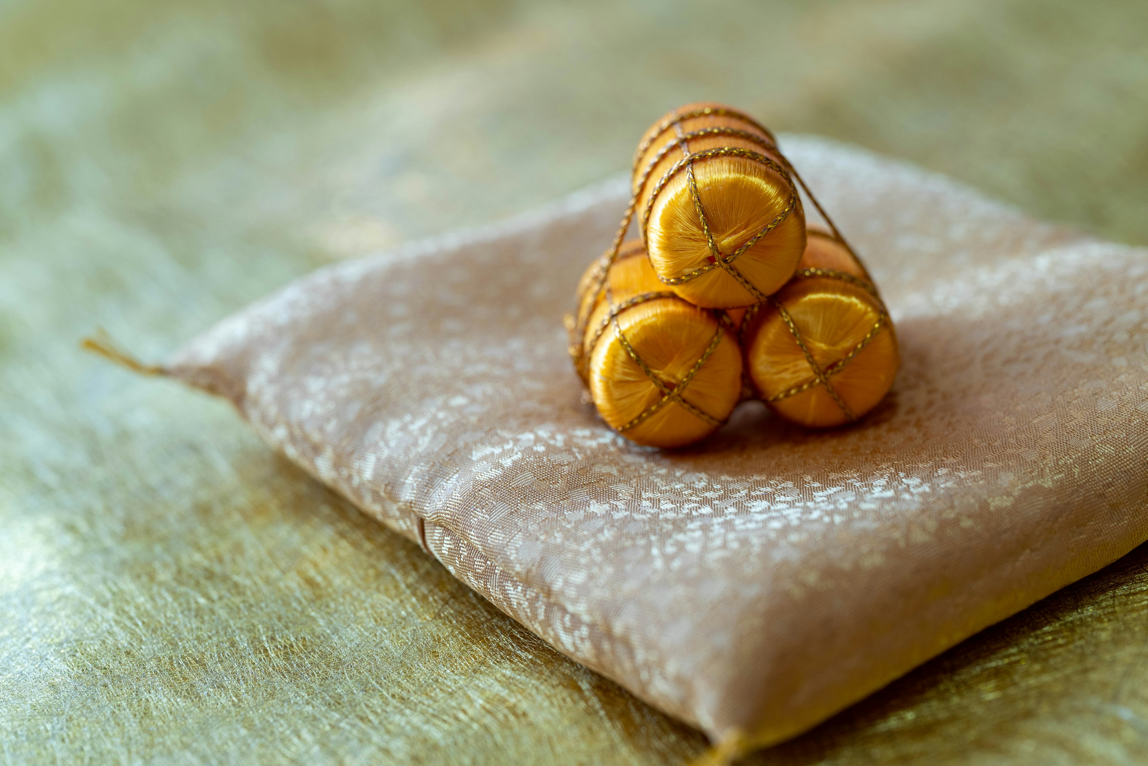 Primo piano di tre dolci rotondi dorati impilati su un cuscino beige morbido