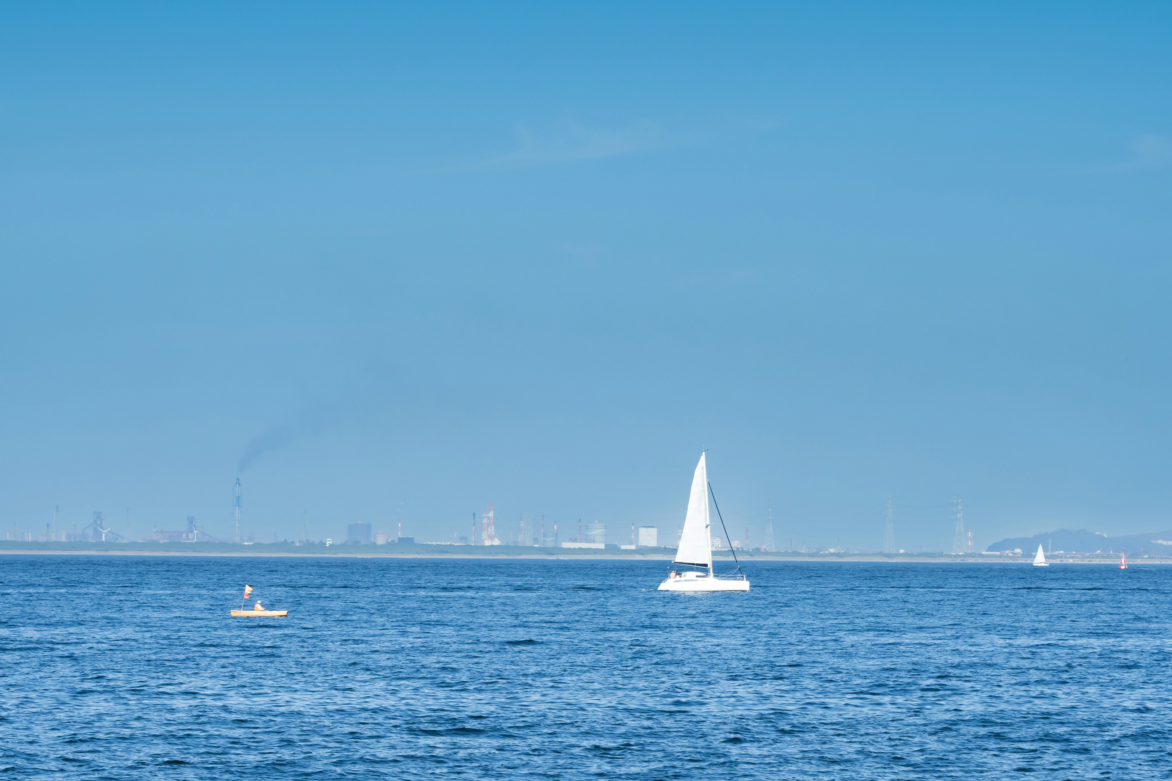 A white sailboat on a blue ocean under a clear sky