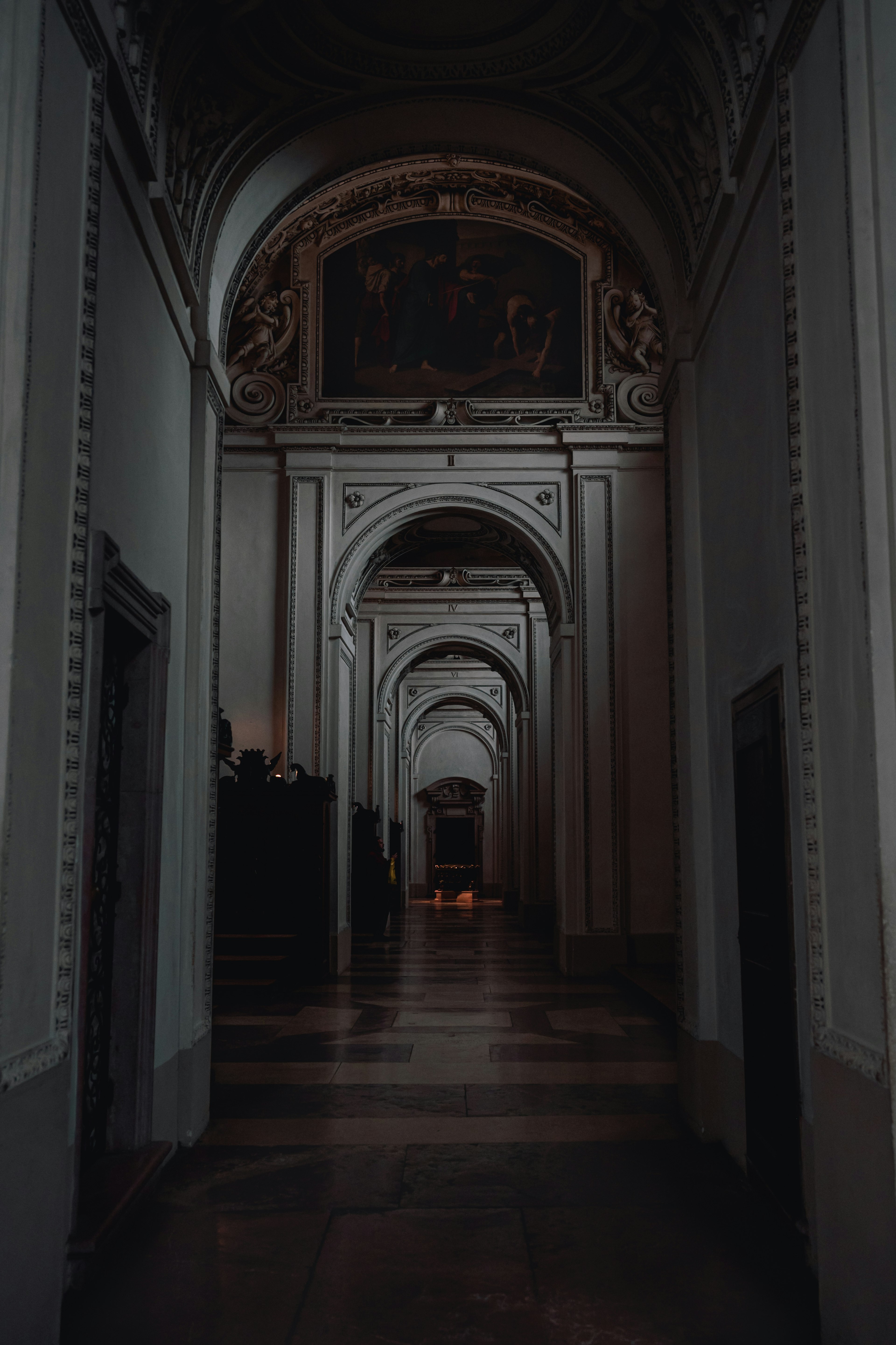 A dimly lit corridor featuring arched ceilings and decorative walls