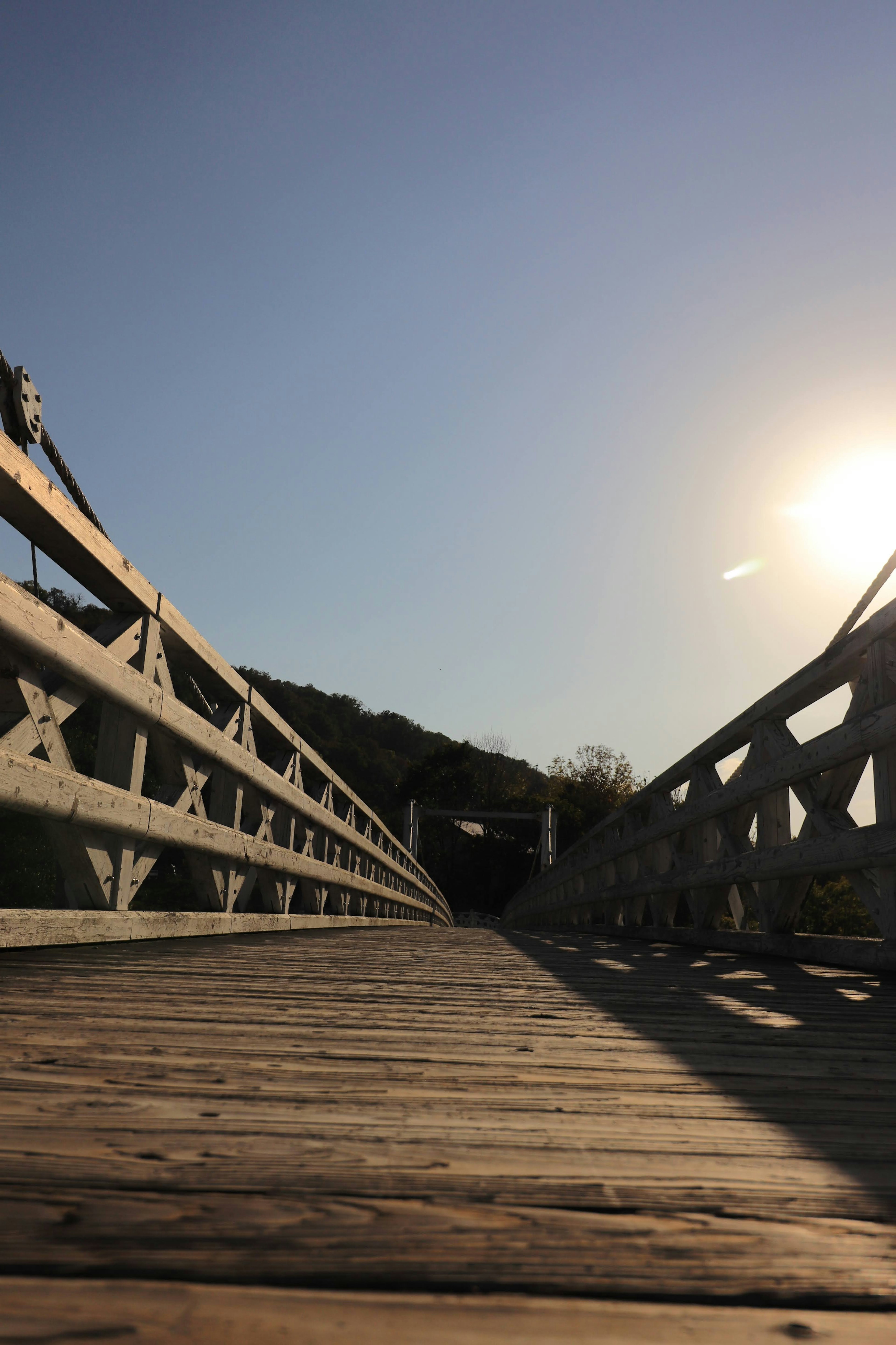 Un puente de madera que conduce hacia el cielo con luz solar brillante iluminando la escena