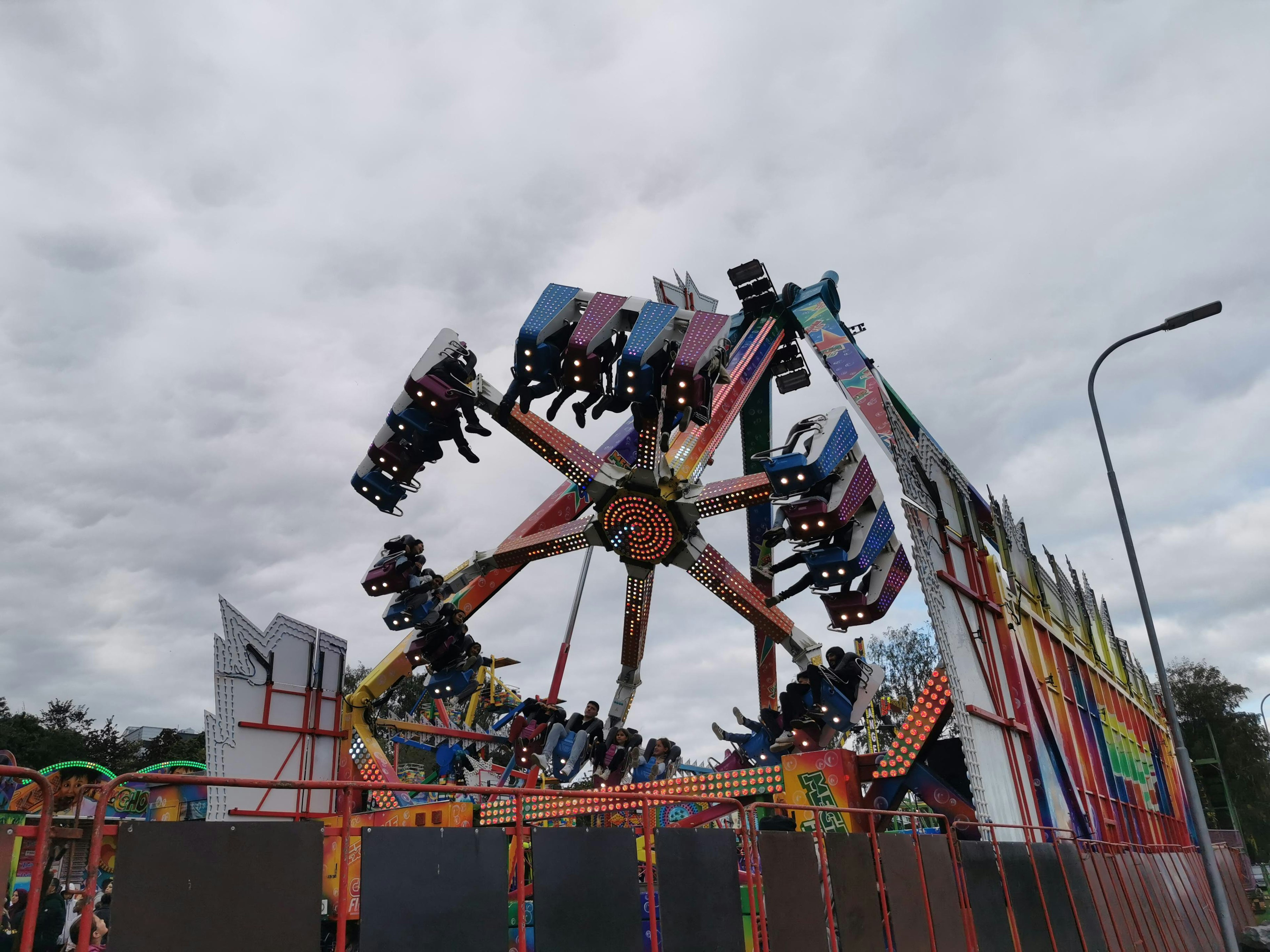 Bunte Fahrgeschäfte im Vergnügungspark bei bewölktem Himmel