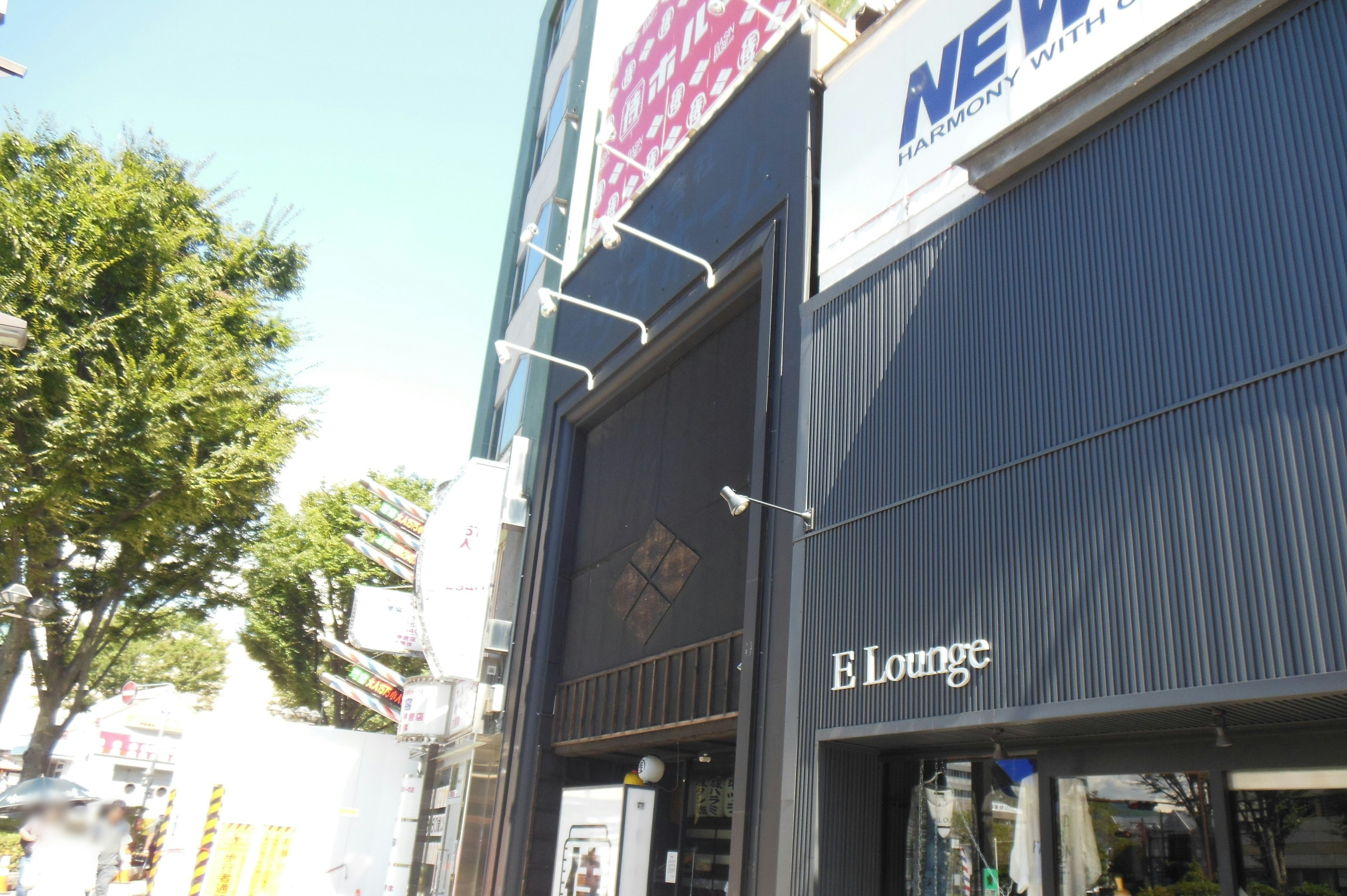 Bâtiment de l'E Lounge avec façade noire et arbres à proximité