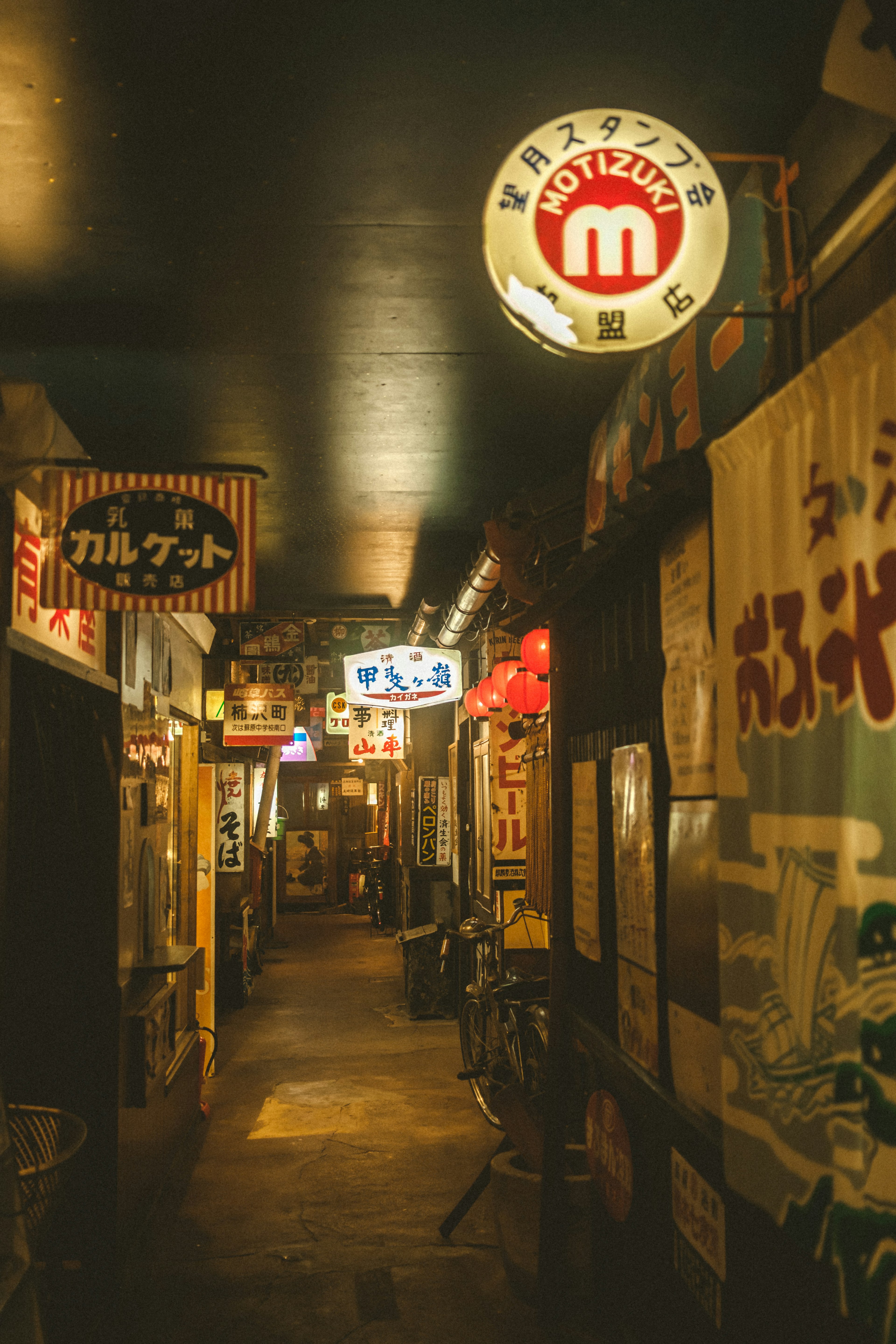 暗い通路に並ぶ飲食店の看板とネオンの明かり