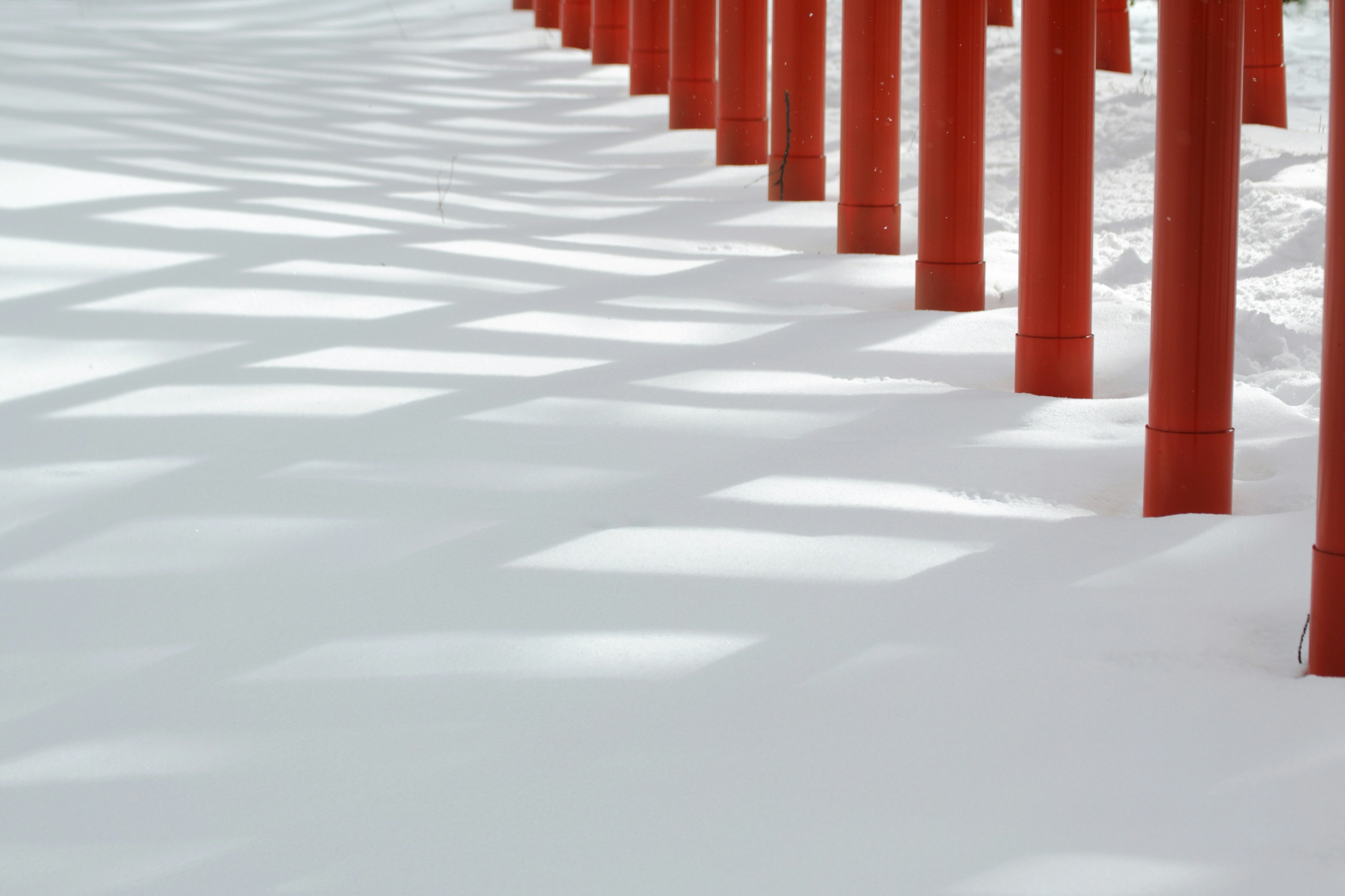 Pilares rojos proyectando sombras sobre la nieve blanca