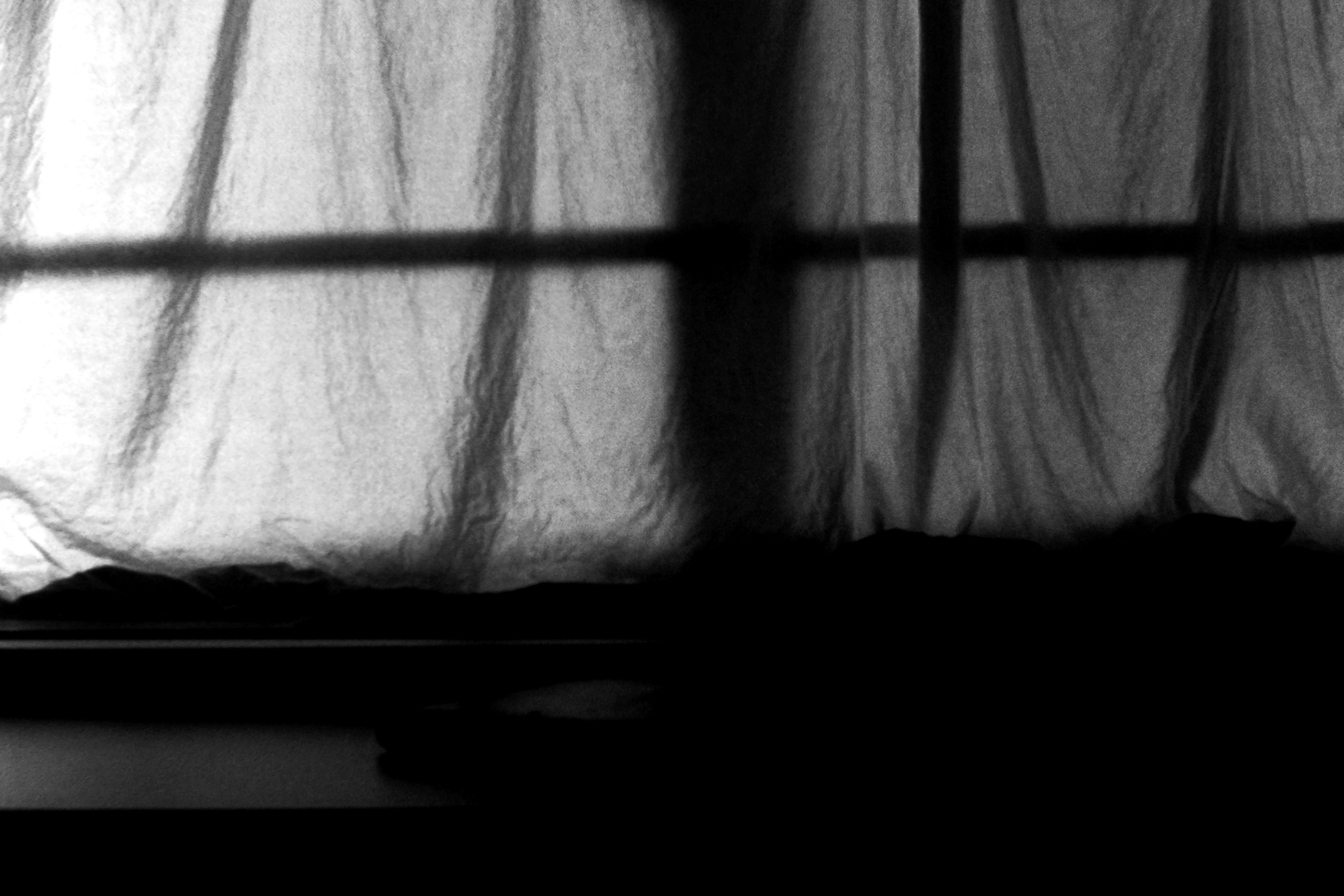 Escena en blanco y negro con cortinas bloqueando la luz y sombras proyectadas