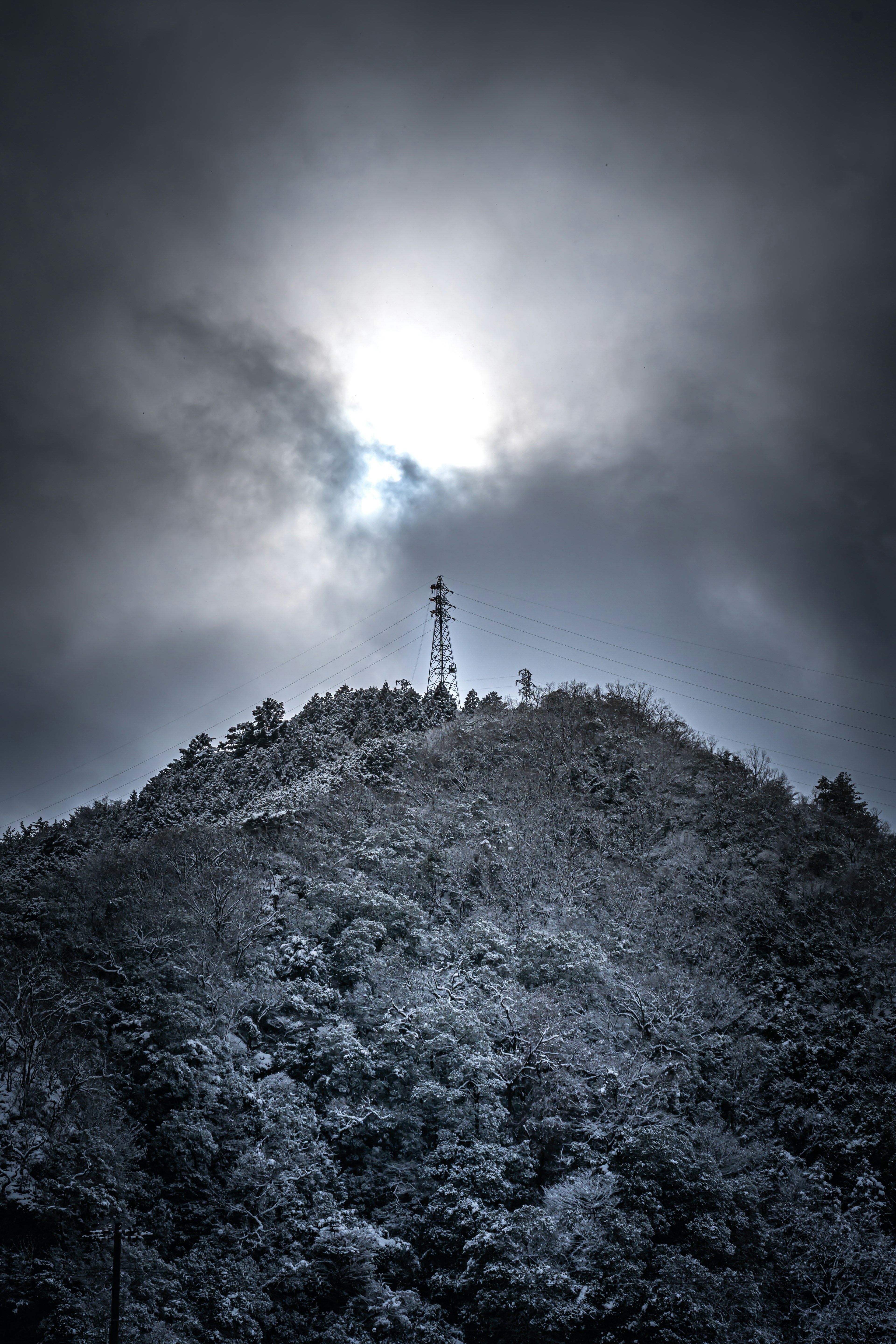 Puncak gunung yang tertutup salju dengan menara komunikasi dan langit mendung