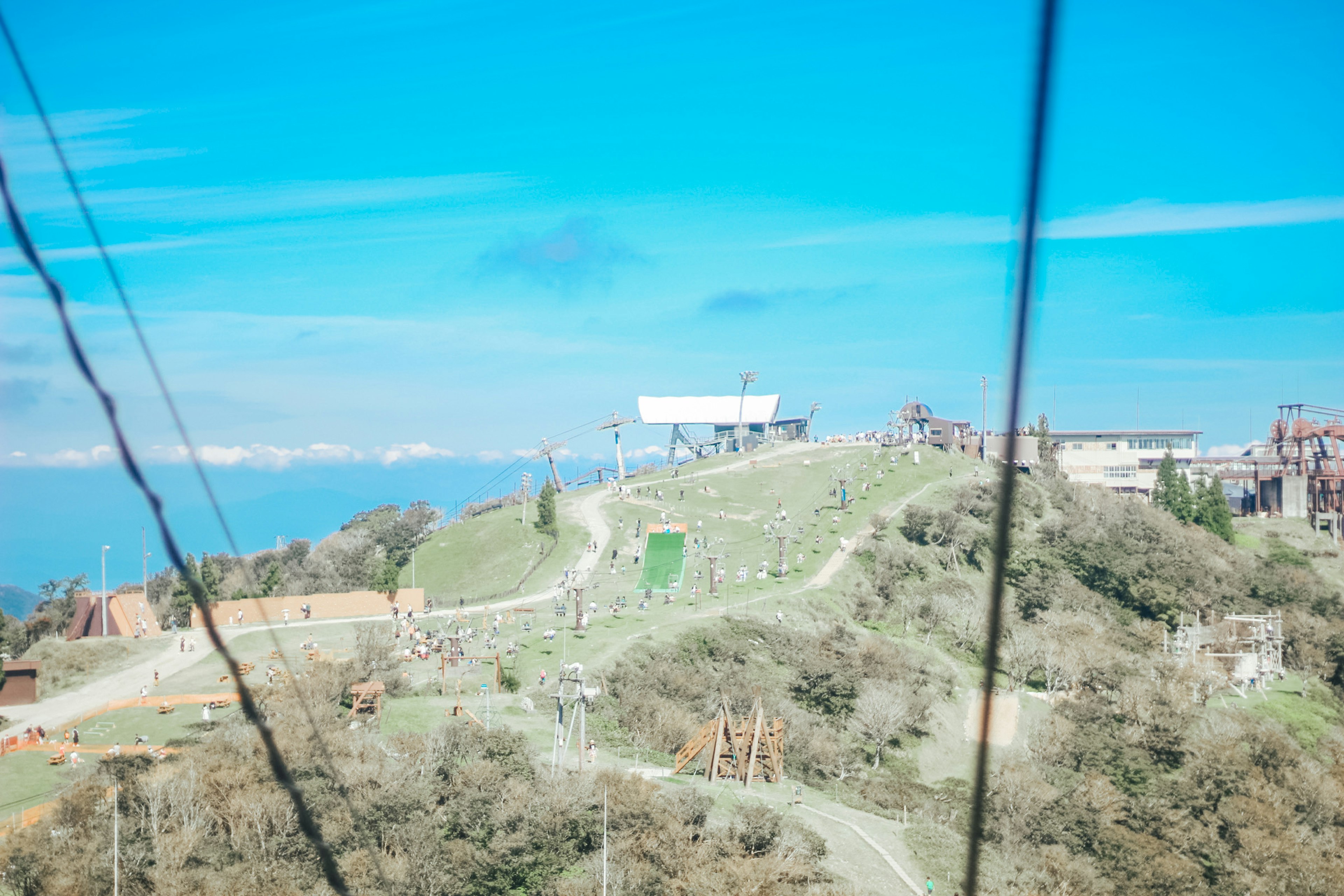 Green hillside under blue sky with cable car station