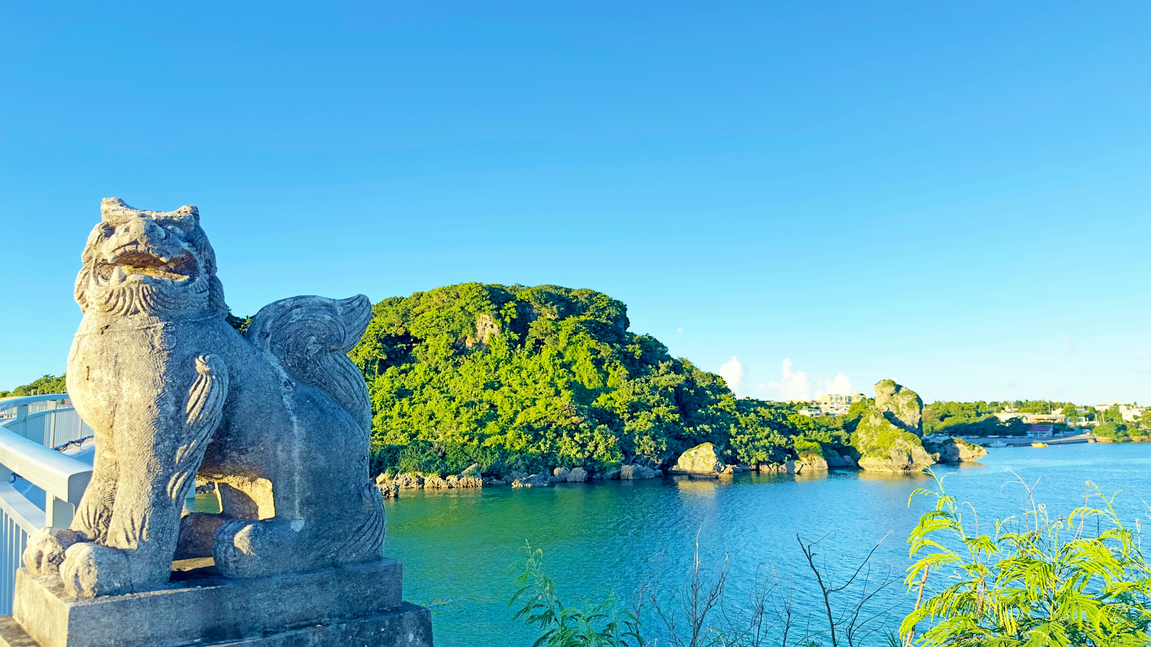 Stone lion statue overlooking a serene blue lake and green island