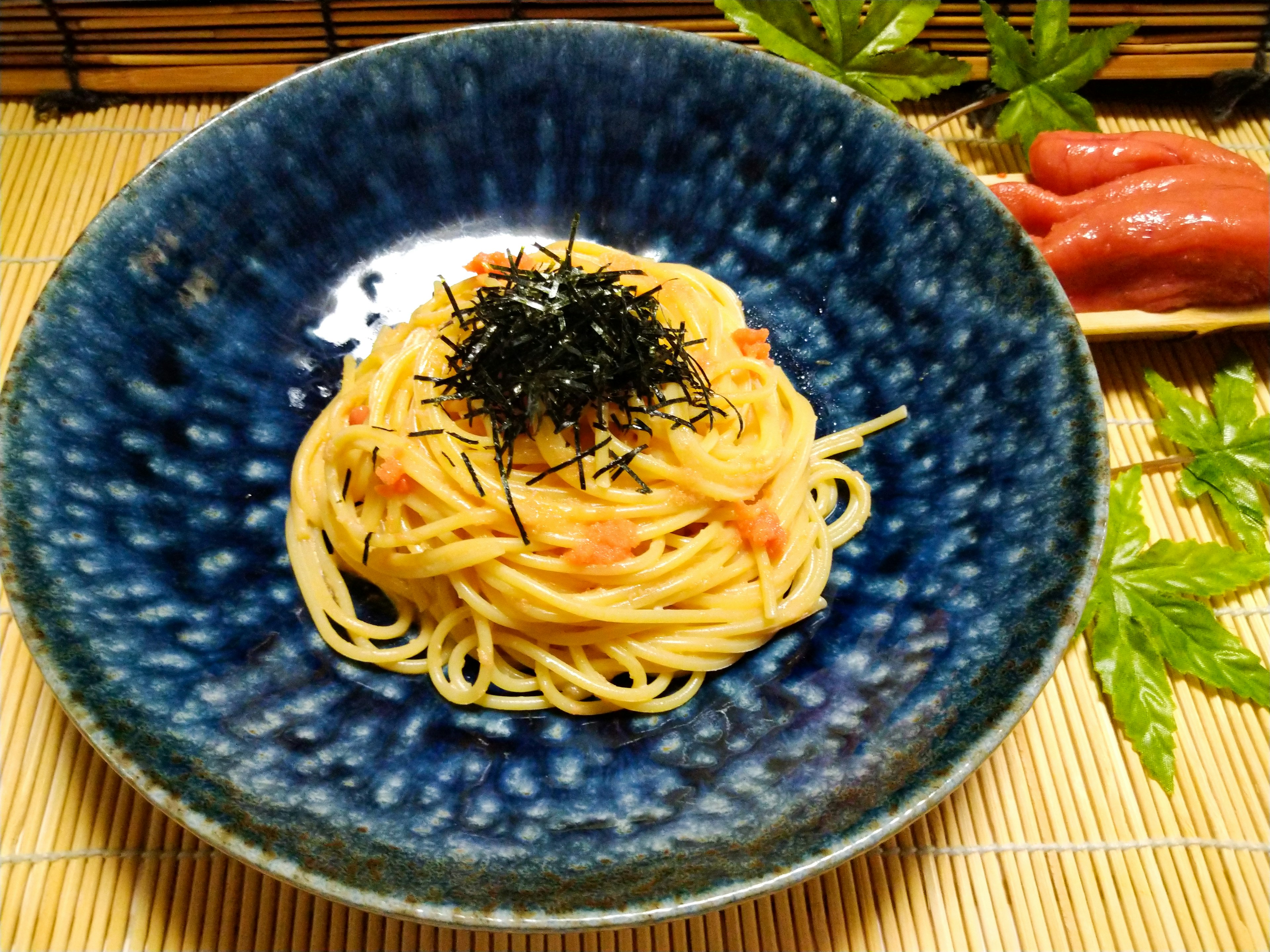 Pasta served in a blue bowl topped with seaweed