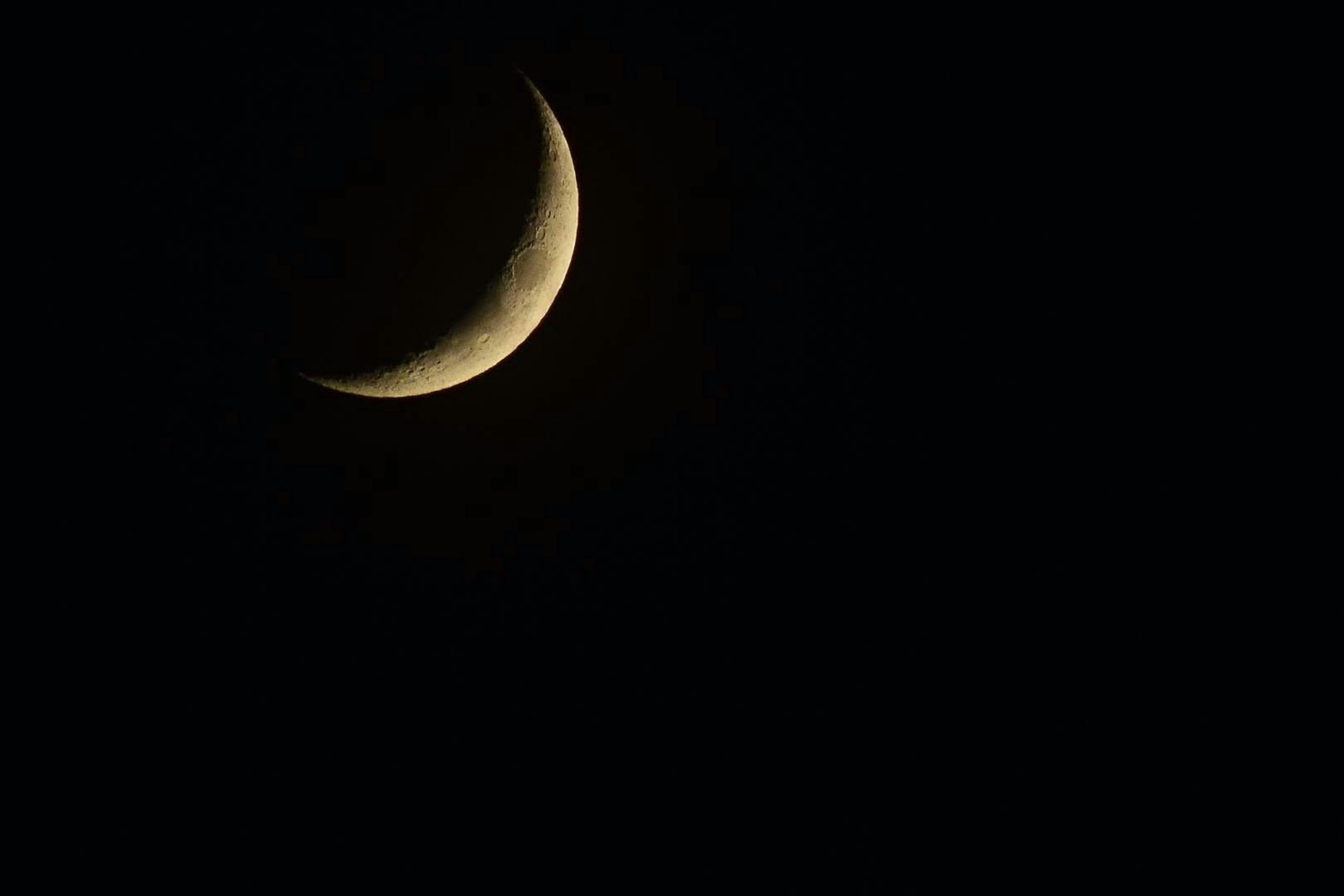 Luna creciente delgada sobre un fondo oscuro