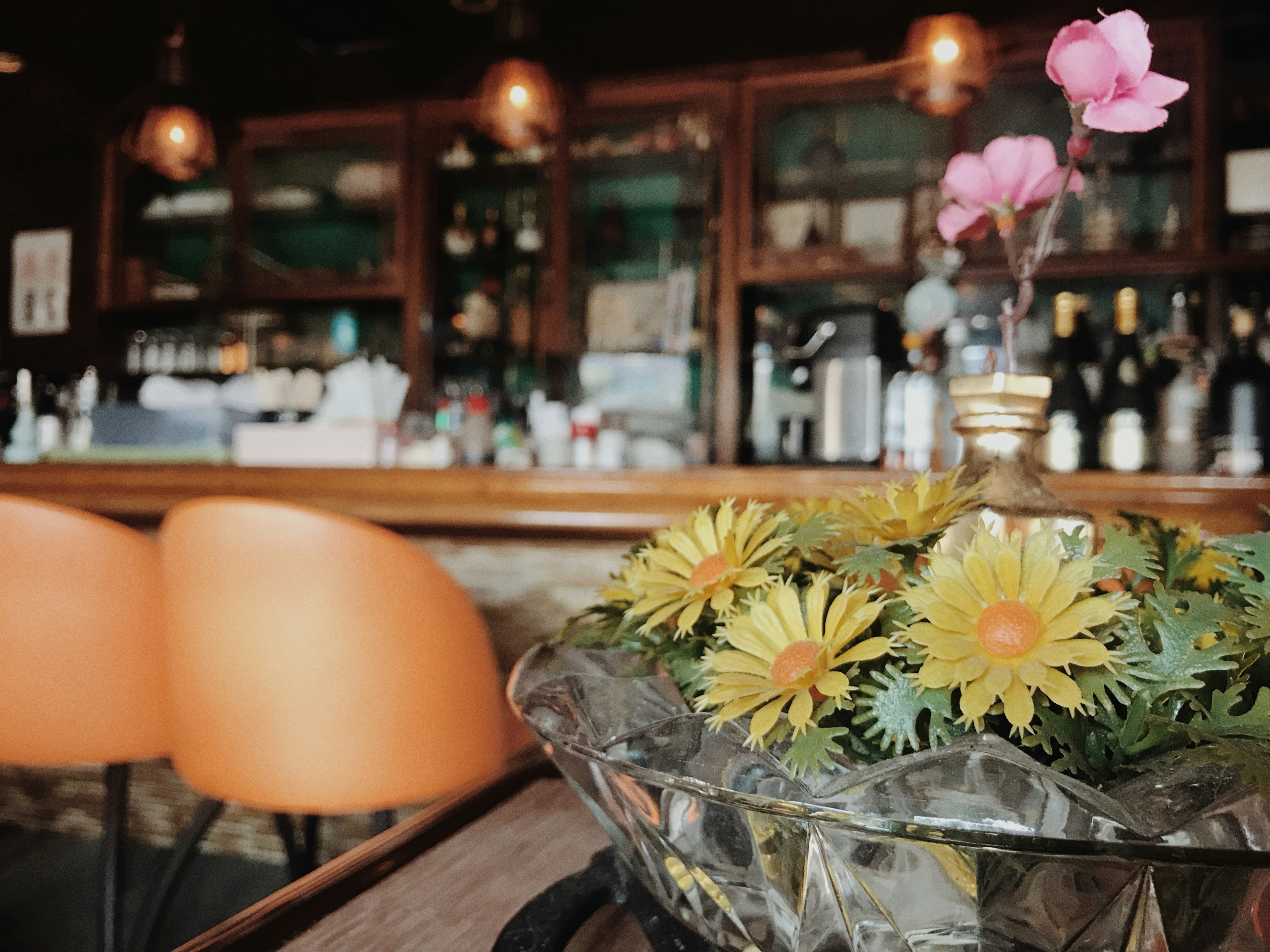 Interno di un caffè accogliente con un bar sullo sfondo e sedie arancioni