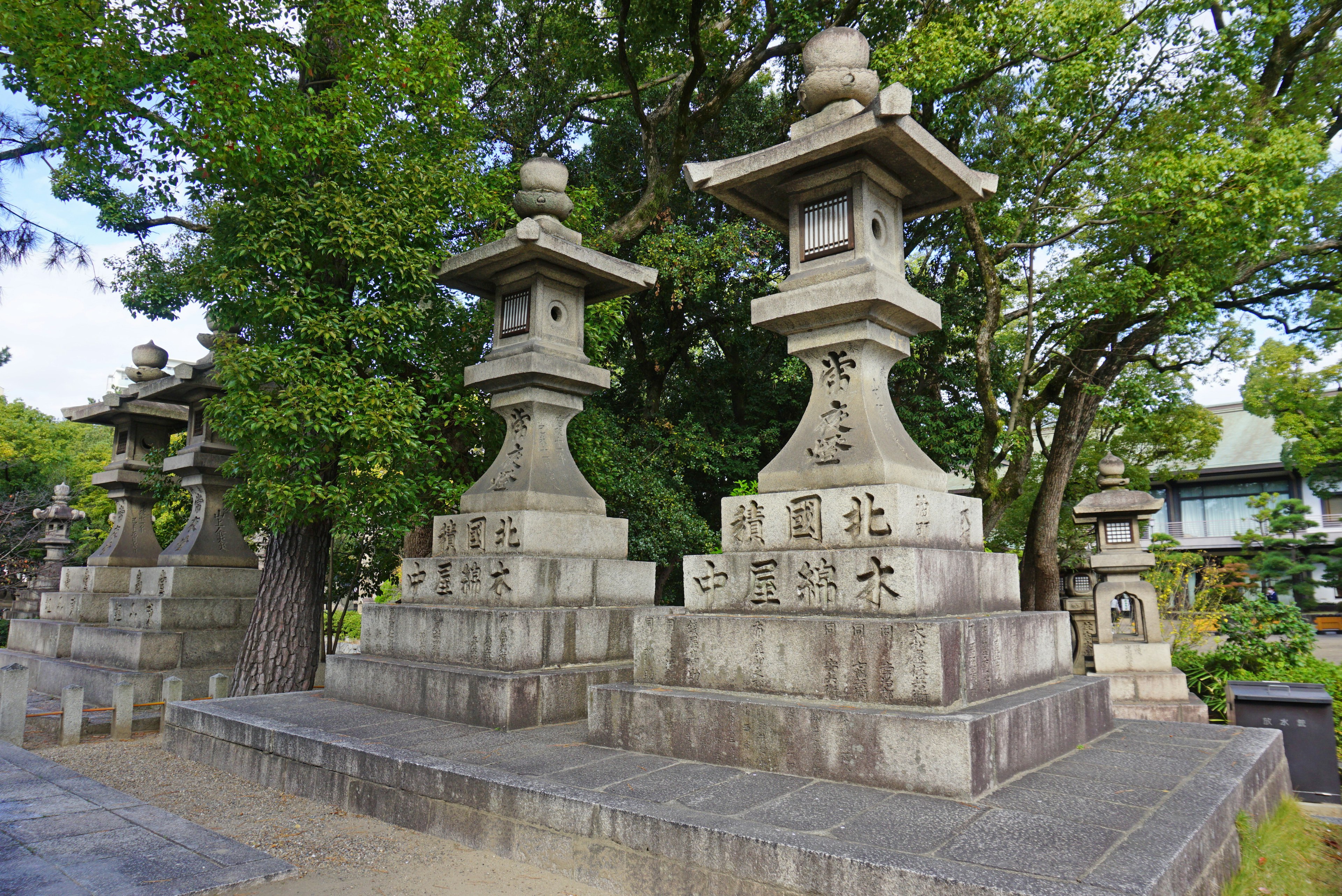 Traditionelle japanische Steinfackeln in einem ruhigen Garten, umgeben von üppigen Bäumen