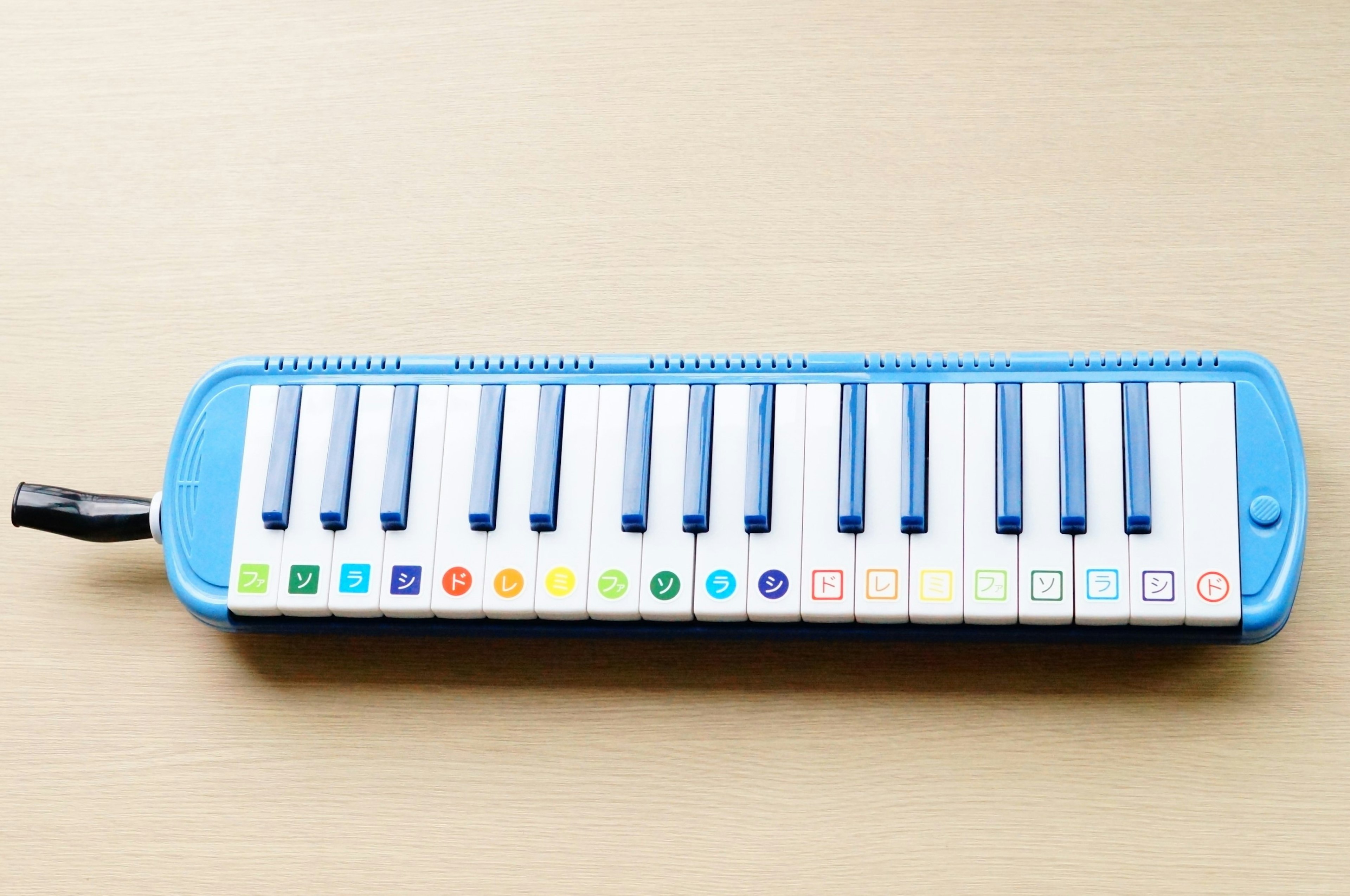 Blue melodica with white keys and colorful buttons on top