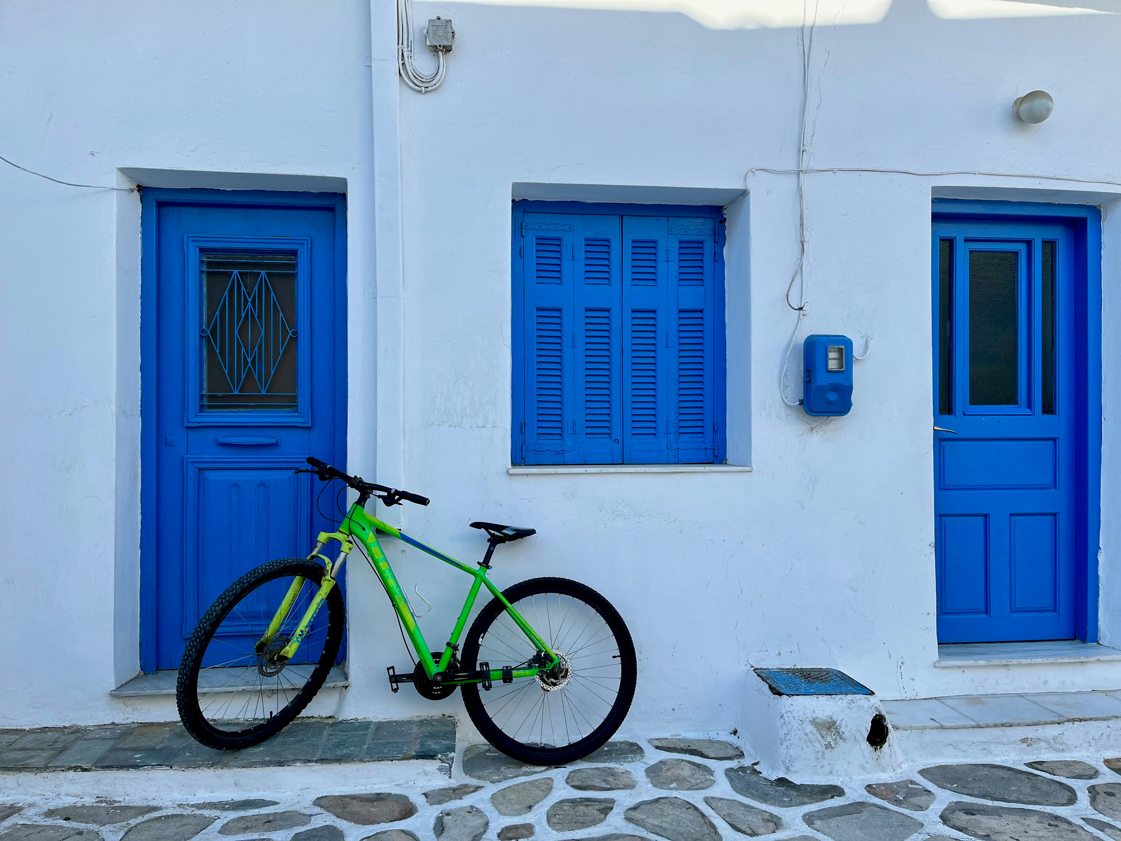 Weißes Haus mit blauen Türen und einem grünen Fahrrad