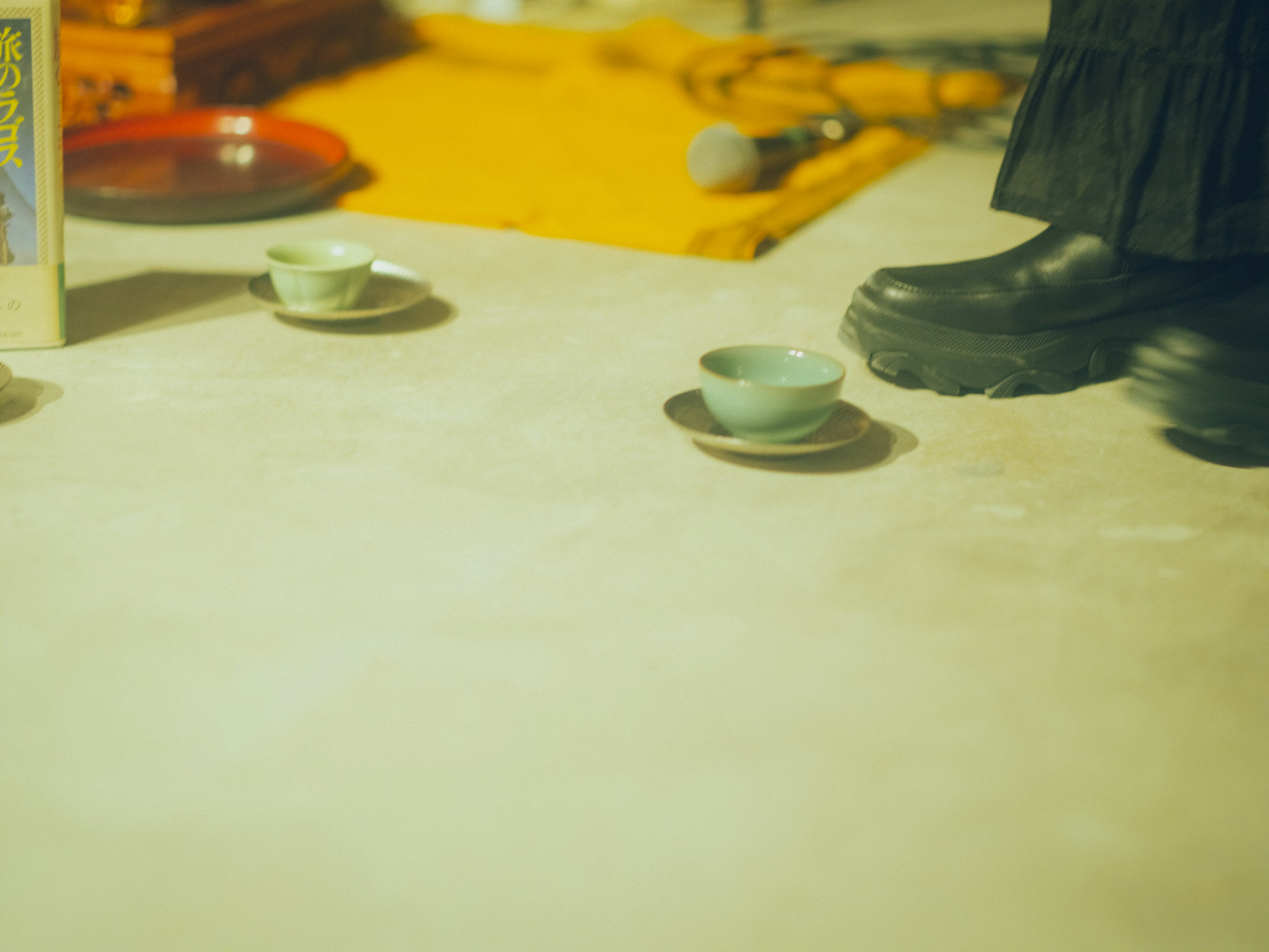 Scene featuring small tea cups on the floor and black boots