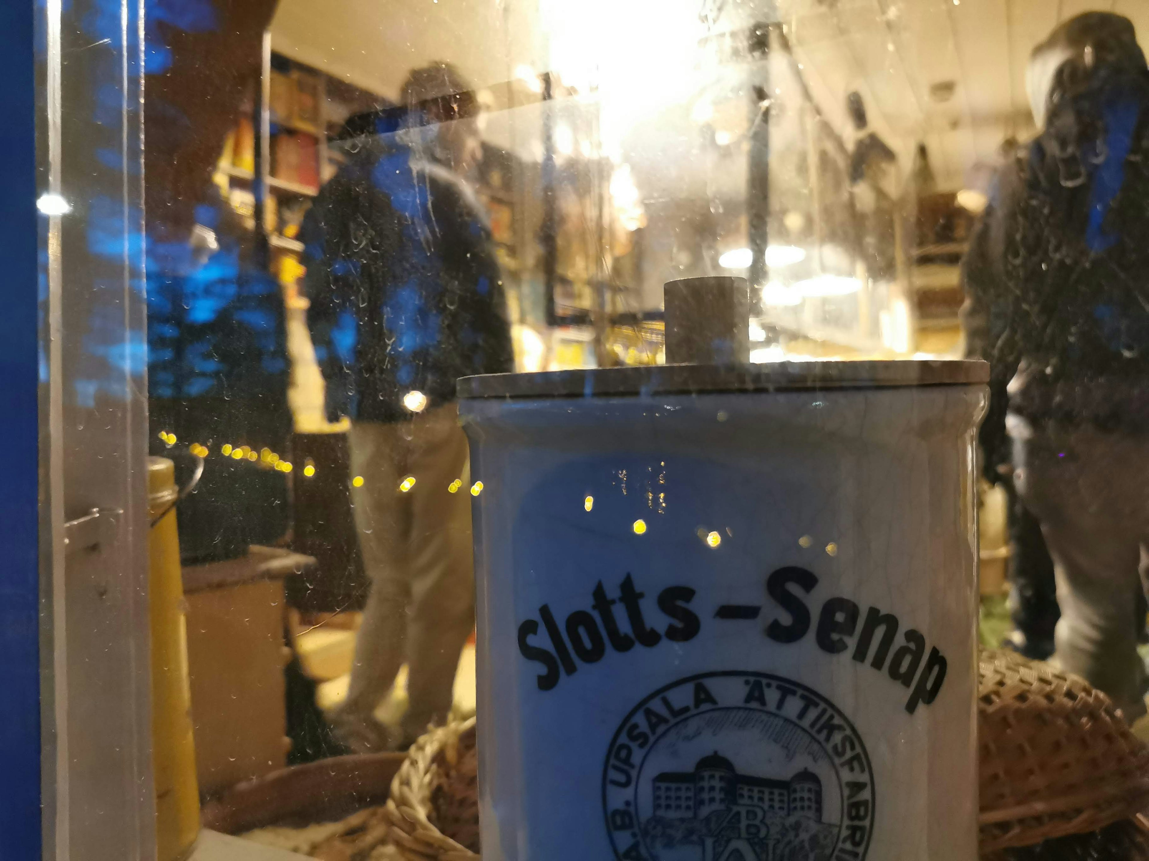 View of people through a window with a Slotts-Senap jar in the foreground