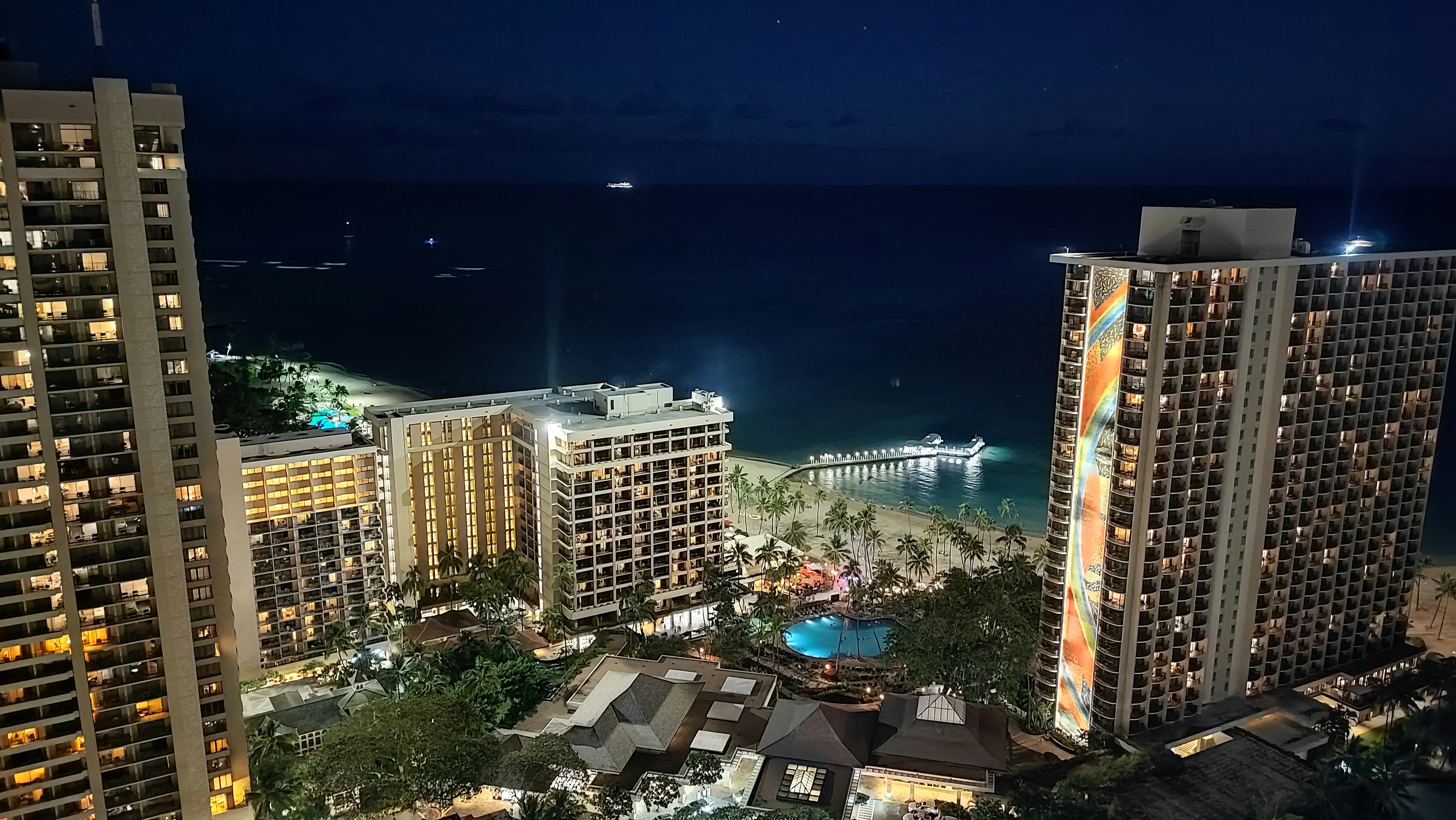 Vue nocturne de Honolulu avec des immeubles et l'océan