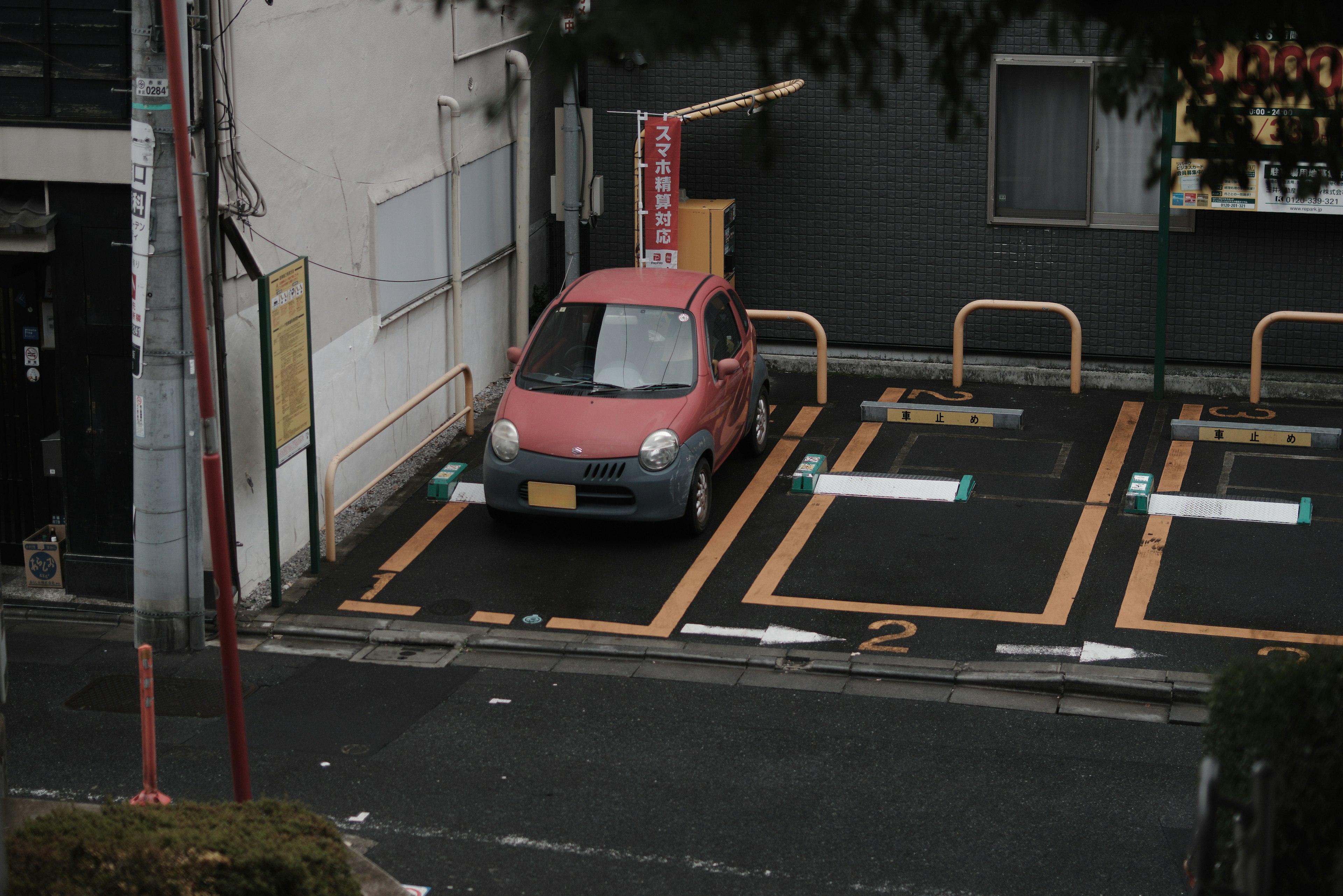 Une voiture rose garée dans un parking avec des infrastructures environnantes