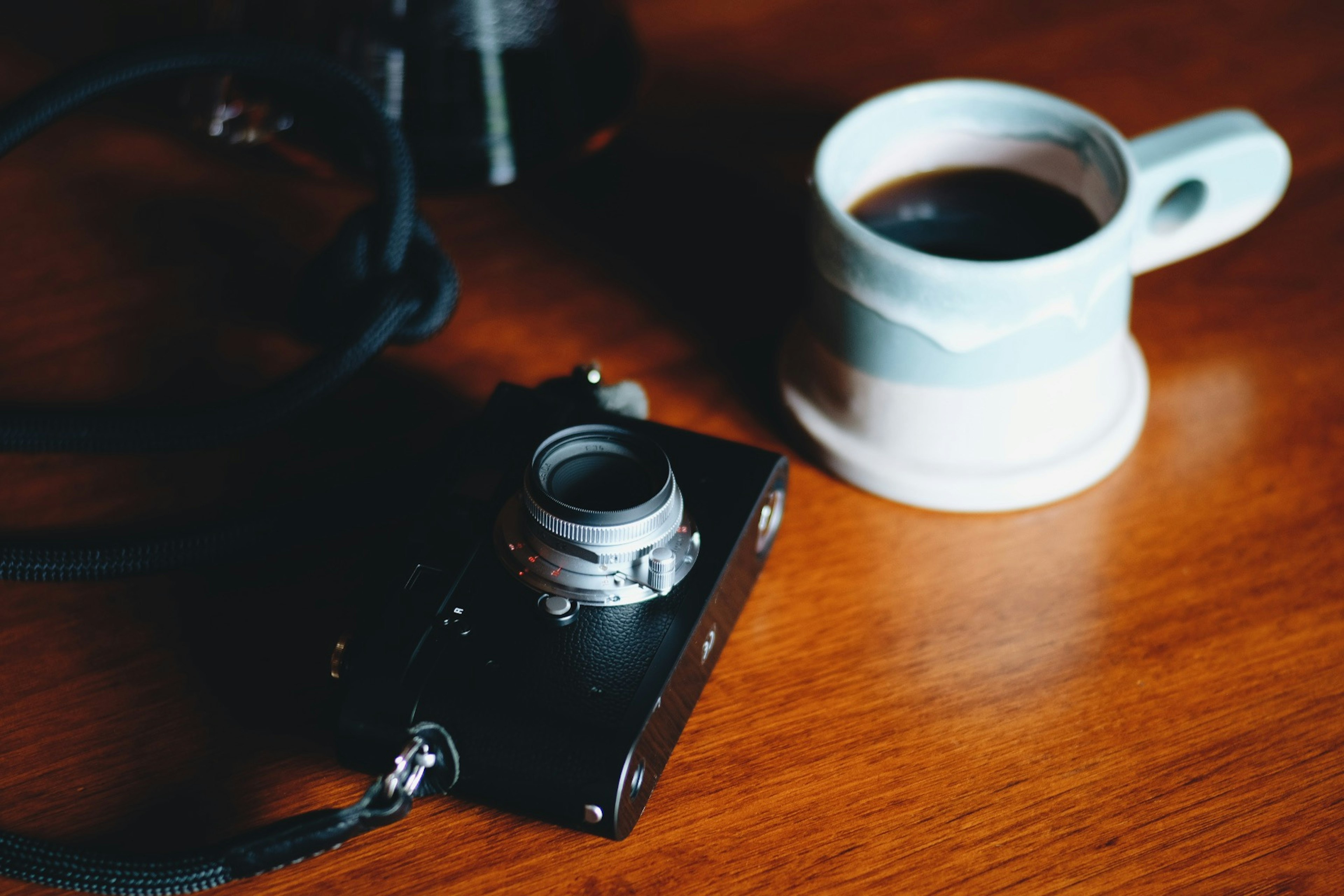 A camera and a coffee cup placed on a wooden table