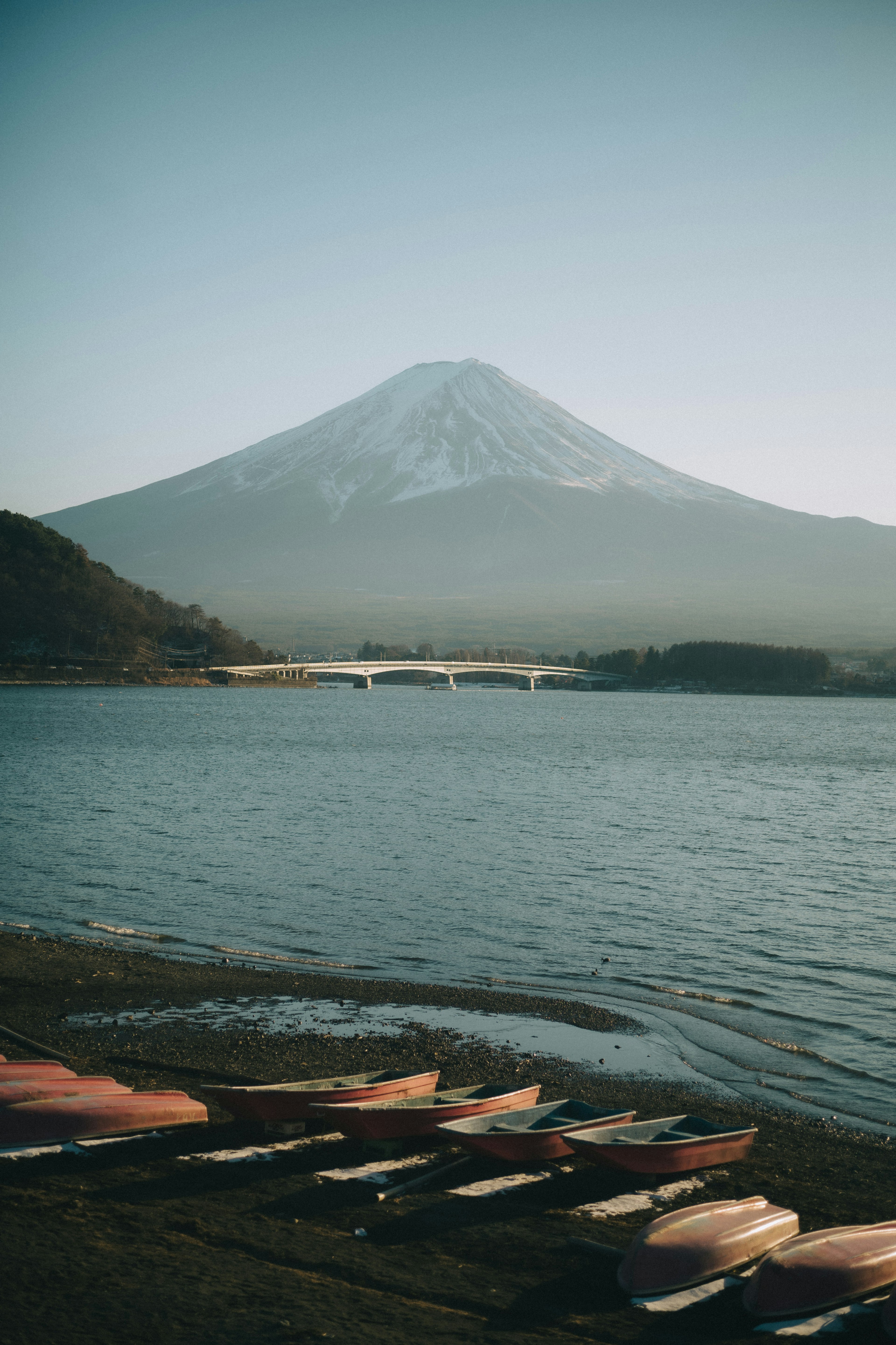 เรือคายัคเรียงรายอยู่ที่ชายฝั่งพร้อมภูเขาฟูจิในพื้นหลัง