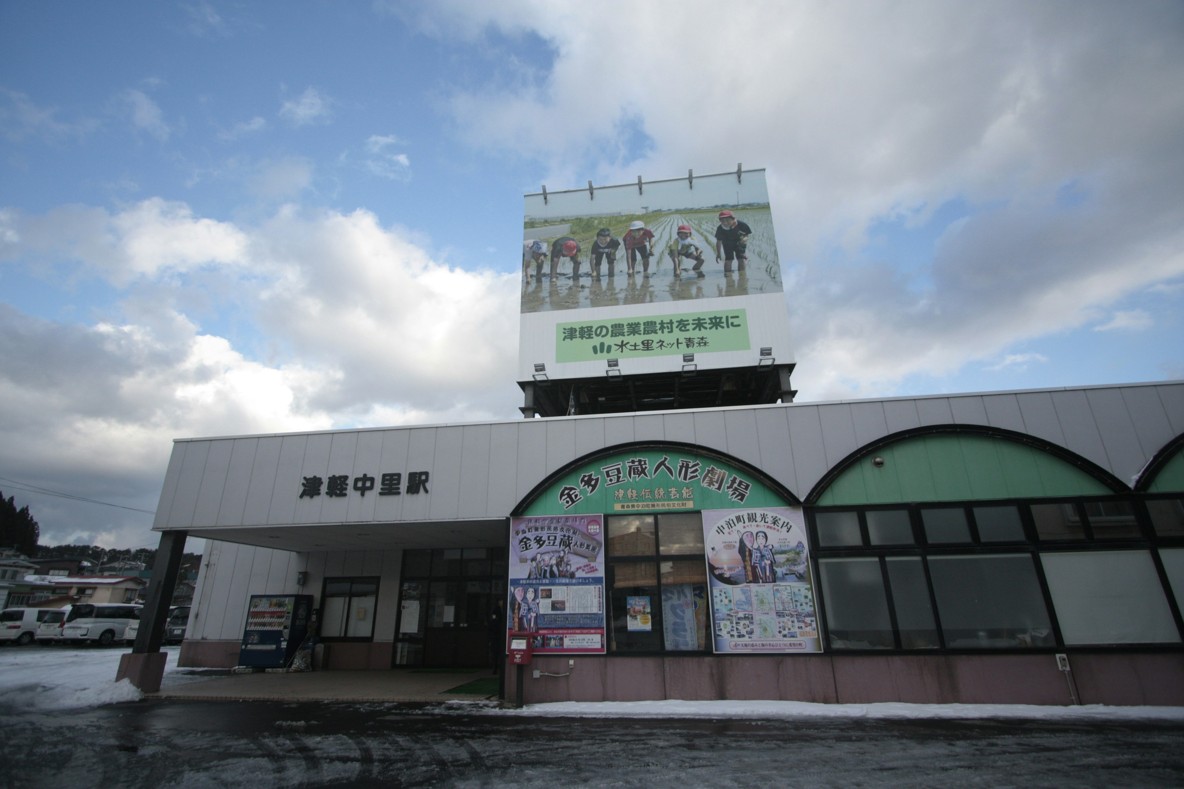 Un edificio de estación con un gran cartel y cielo nublado